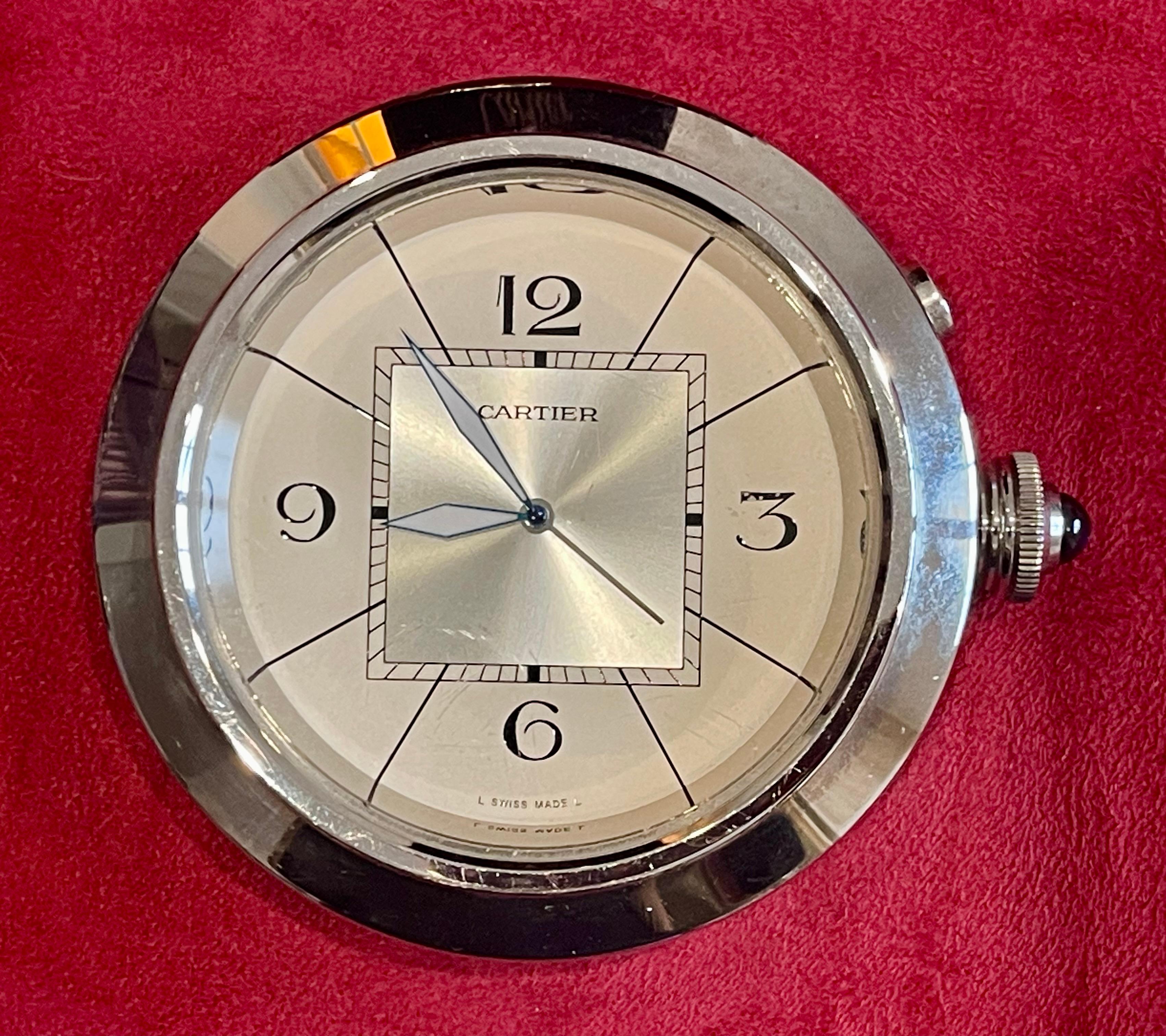 Cartier Pasha travel alarm clock in silver-plated steel. Presented in its original box, it has never been used. It features a side adjustment button with a blue cabochon. It is in perfect condition and operates with a quartz movement. Signed on the