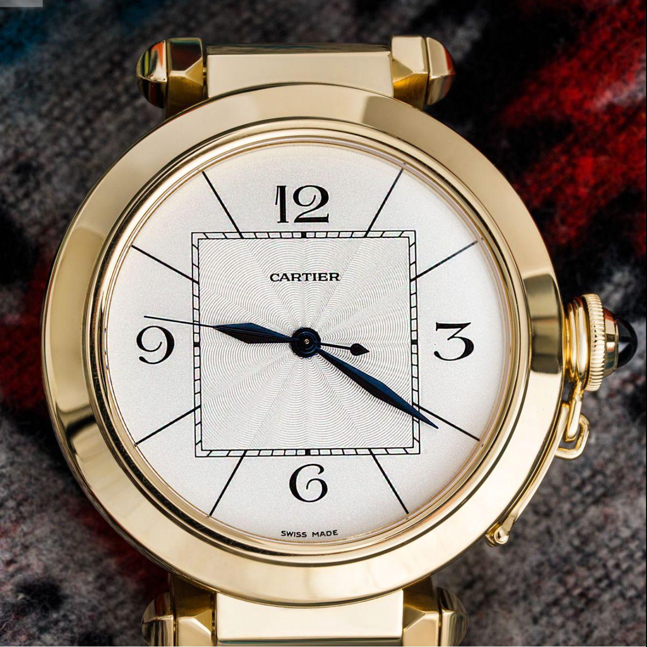 A 42mm Pasha in yellow gold by Cartier. Featuring a silver dial with a guilloche centre, sword-shaped hands in blued steel, a yellow bezel and a screw-down cover set with a cabochon.

The bracelet comes with a concealed double deployant clasp, both