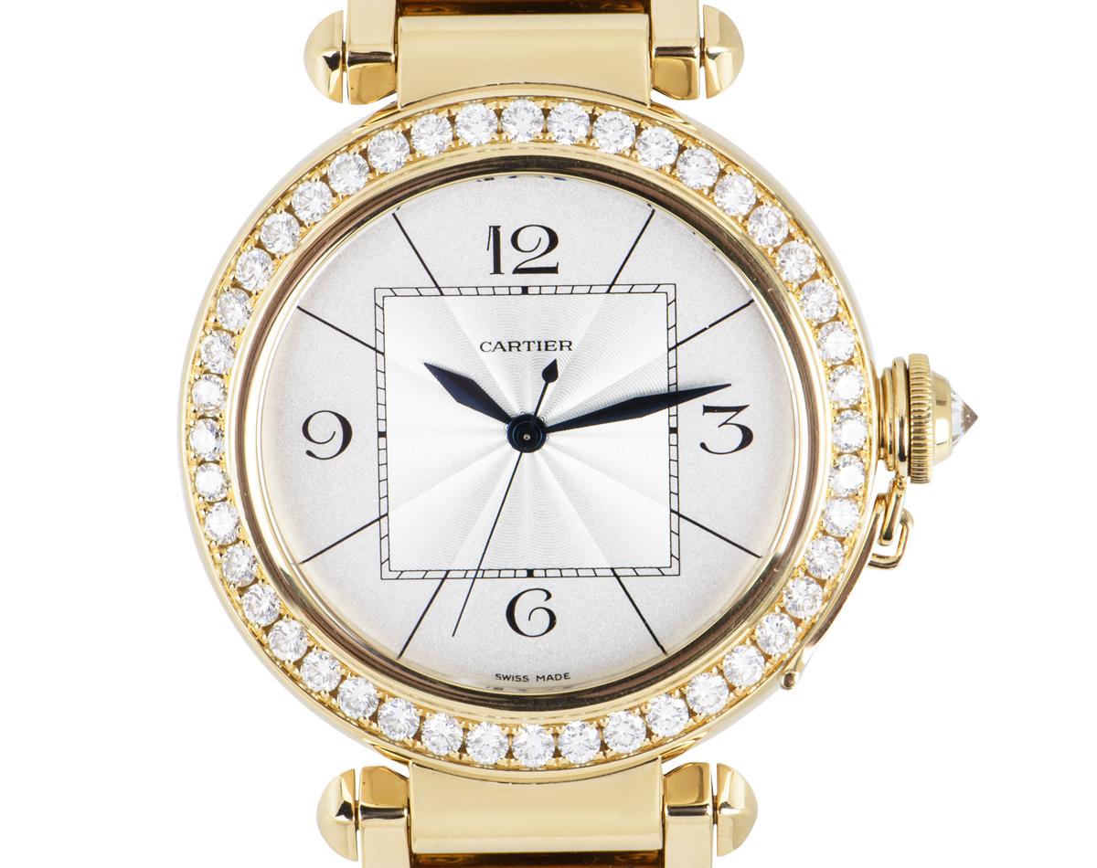 A 42mm Pasha in yellow gold by Cartier, featuring a silver dial with a guilloche centre and sword-shaped hands in blued steel. The bezel is set with 42 round brilliant cut diamonds and the crown, protected by a screw-down cover set with a single