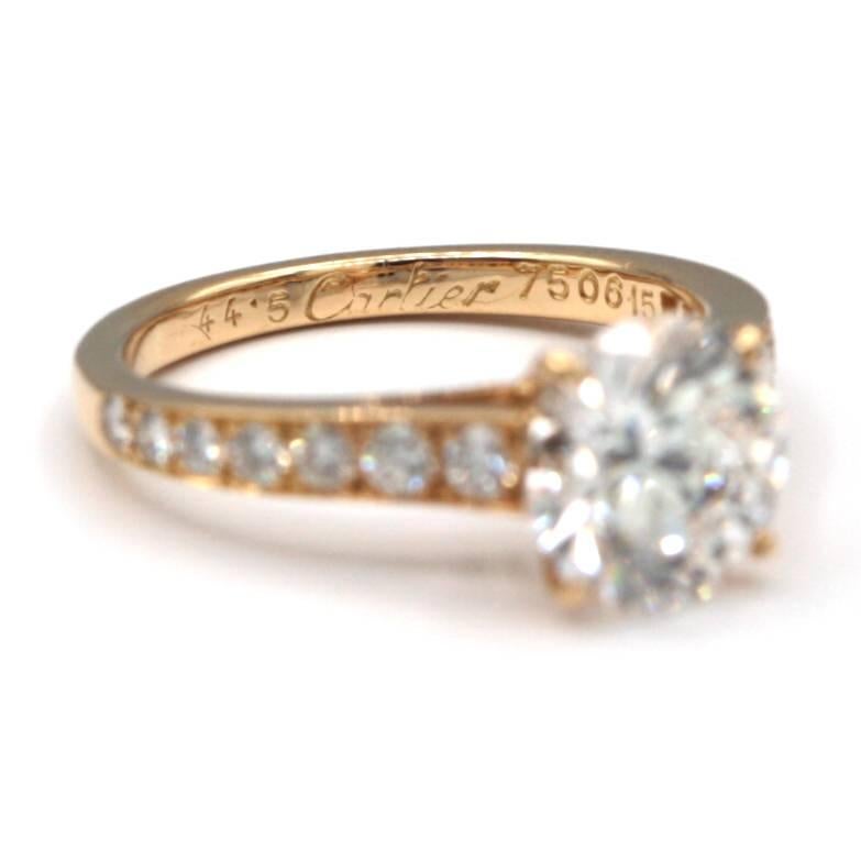 This Cartier ring is stamped 750 /18k Yellow Gold, has a prong set with one round brilliant cut diamond, flanked by 14 paved round faceted diamonds. 

It is GIA certified as follows:

Center Diamond: 
Shape/Cut: Round brilliant Cut
Approximate