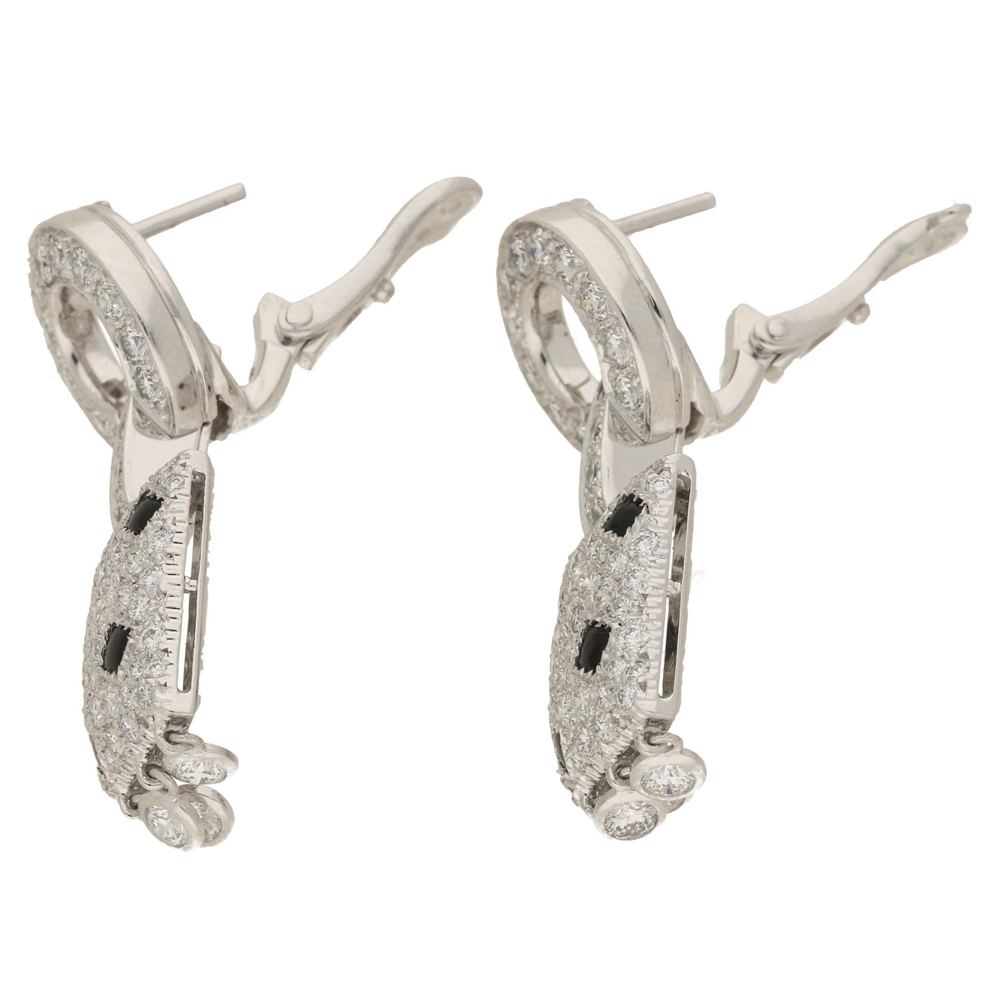 A spectacular pair of signed Cartier Pelage plaque earrings set in 18k white gold. Each earring is of a geometric design, set with round brilliant-cut diamonds and cabochon onyx studs. The plaques supports a fringe of collet-set brilliant-cut