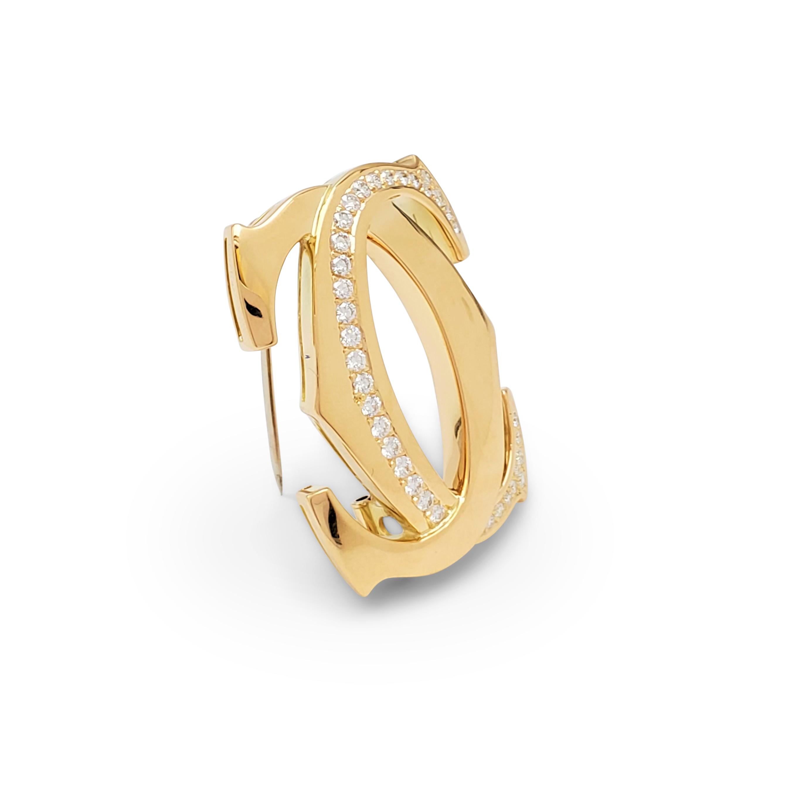 Authentic Cartier 'Penelope' pin crafted in 18 karat yellow gold centers on the iconic interlocking Cartier double-C motif set with an estimated 1.05 carats total weight of round brilliant cut diamonds (E-F color, VS clarity). Signed Cartier, 750,