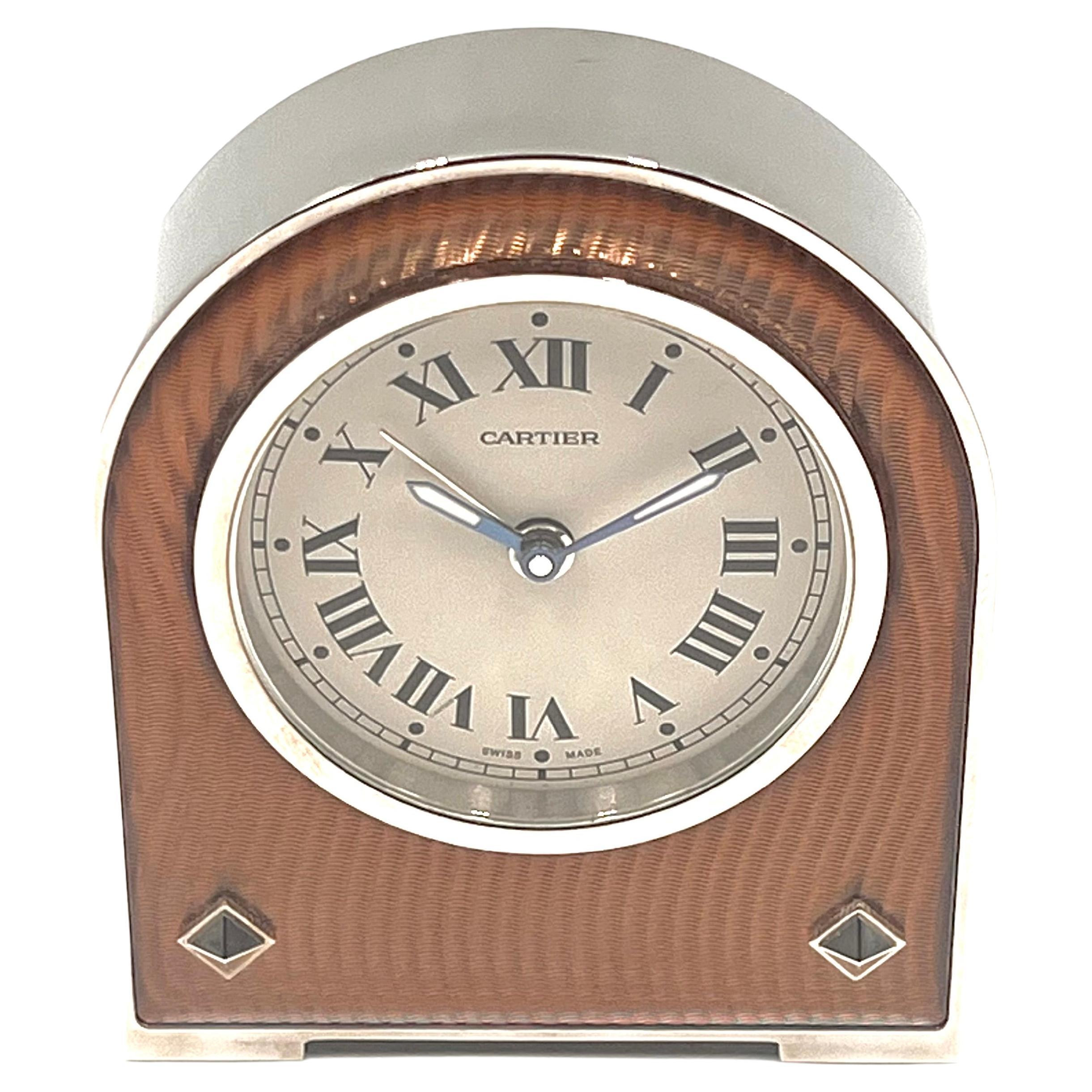 Cartier alarm desk clock in stainless steel, featuring a circular-shaped silvered dial with black Roman numerals; blued steel, dauphene style, luminescent-coated hands with silver-tone seconds hand; front decorated in salmon-pink enamel with a