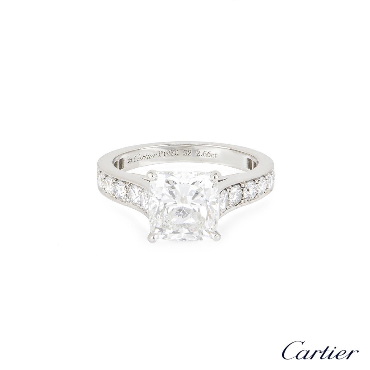A stunning platinum Cartier diamond engagement ring from the 1895 solitaire collection. The ring comprises of a cushion cut diamond in a four claw setting with a weight of 2.66ct, E colour and VS1 clarity. There are 18 round brilliant cut diamonds