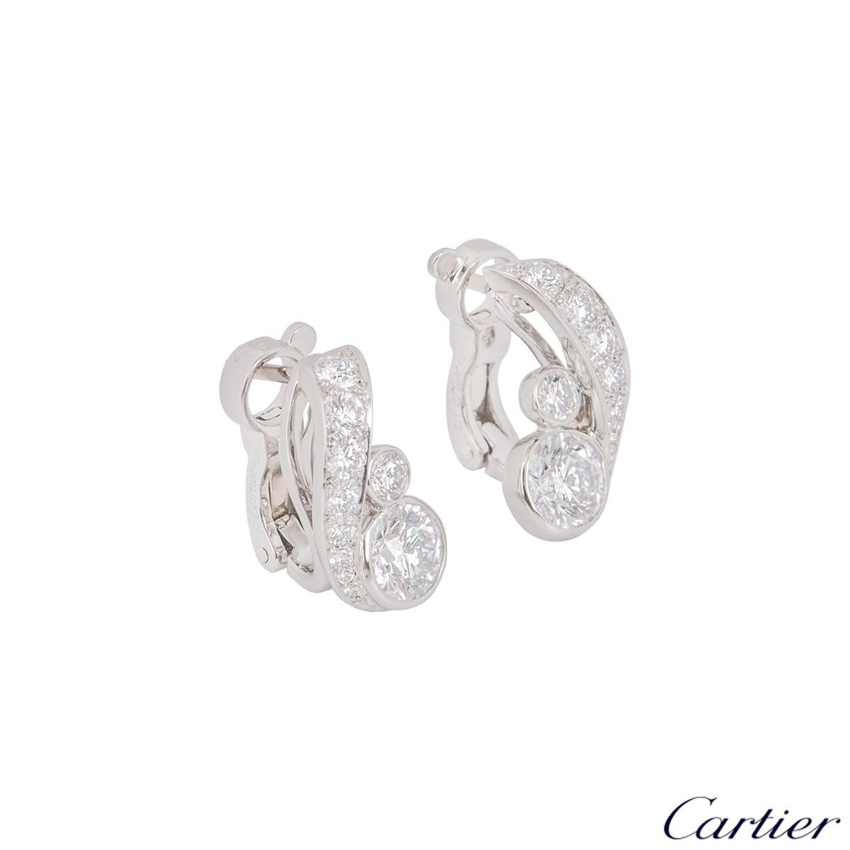 An alluring pair of platinum diamond earrings by Cartier. The earrings each feature 2 round brilliant cut diamonds in a rub over setting, with 8 round brilliant cut diamonds on a stem beside them in a pave setting. The round brilliant cut diamonds