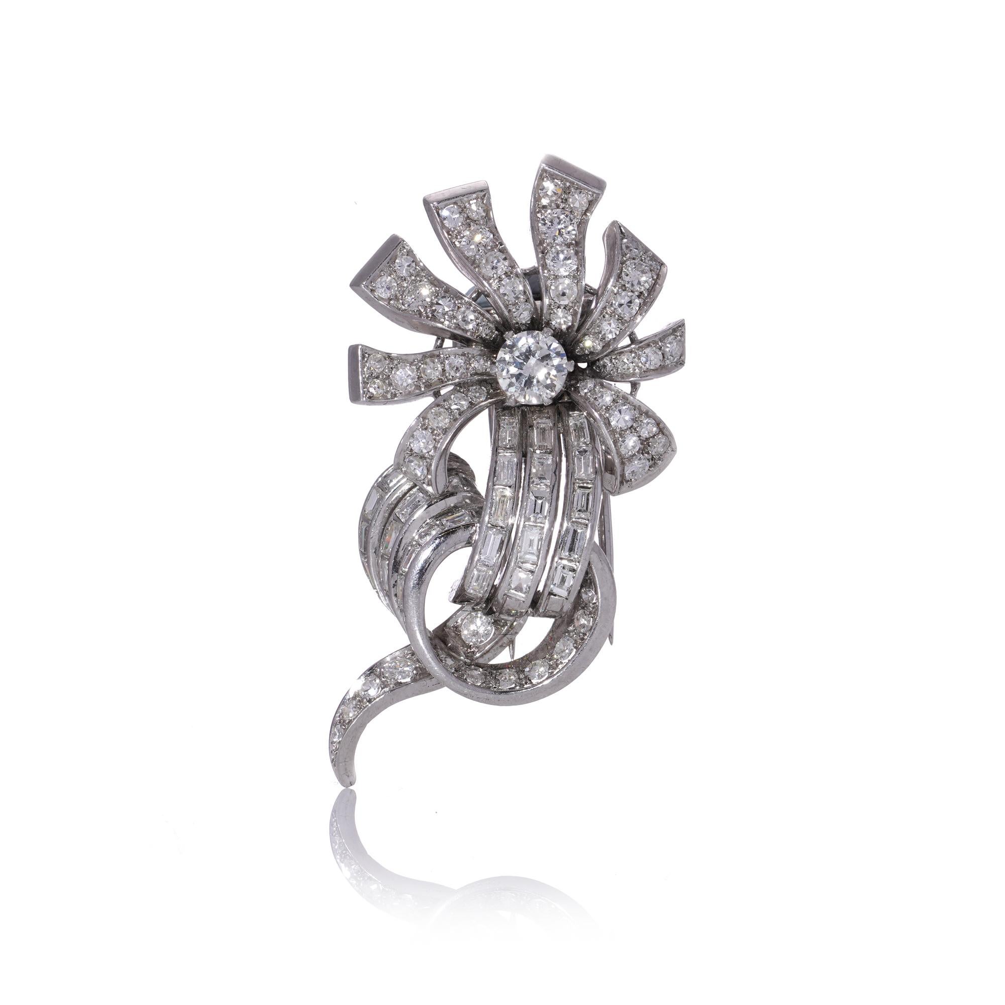 Broche en platine à motif de volutes de fleurs et diamants de Cartier.
Signée Cartier, numérotée.

Cette broche, créée par Cartier dans les années 1950, présente un motif sophistiqué de tiges et de volutes. Elle est ornée d'un mélange de diamants