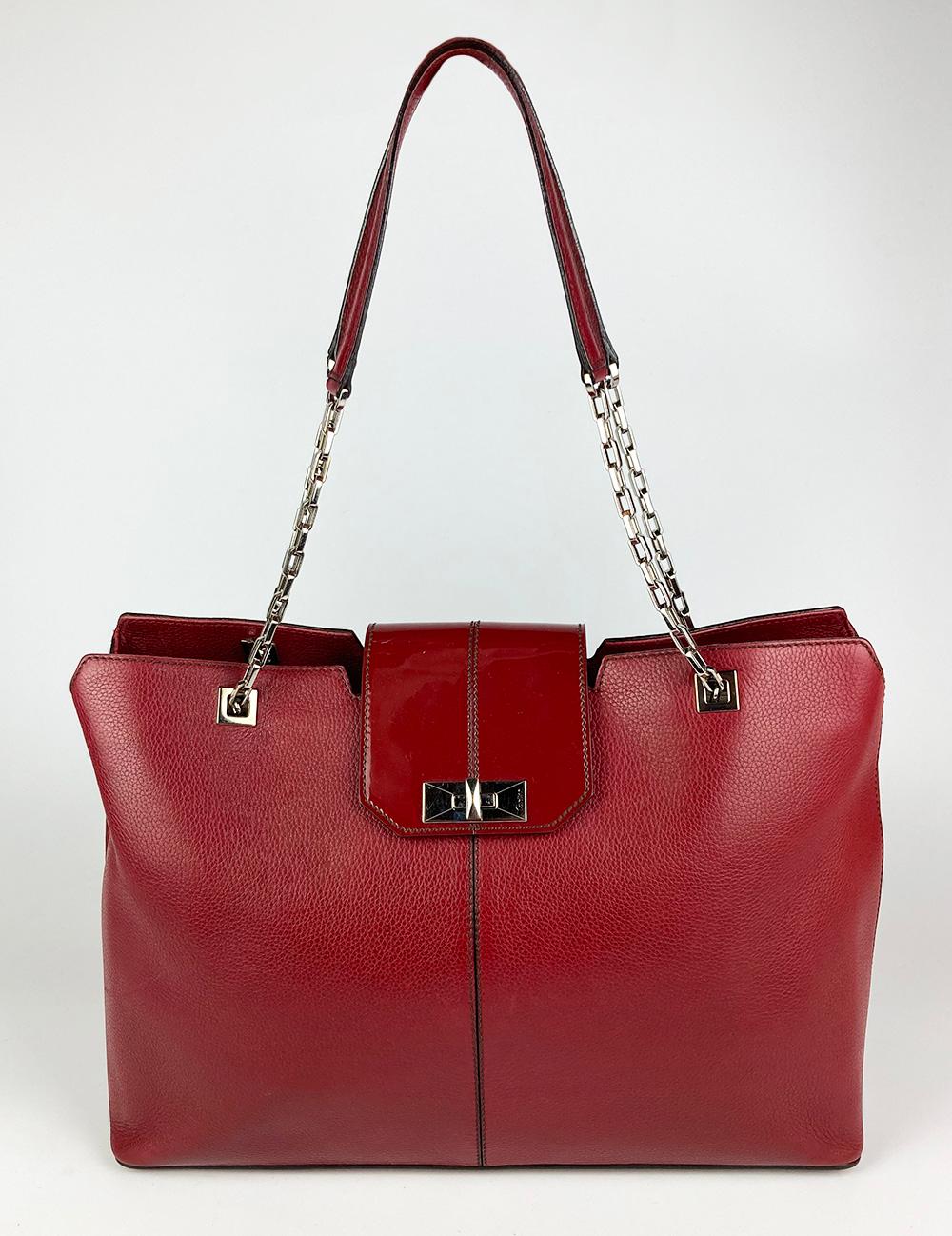 Cartier Red Leather Tote in very good condition. red pebble leather body with patent leather top flap and silver hardware trim. Red leather and silver chain double shoulder strap. 4 silver feet on bottom. Silver mademoiselle twist lock closure opens