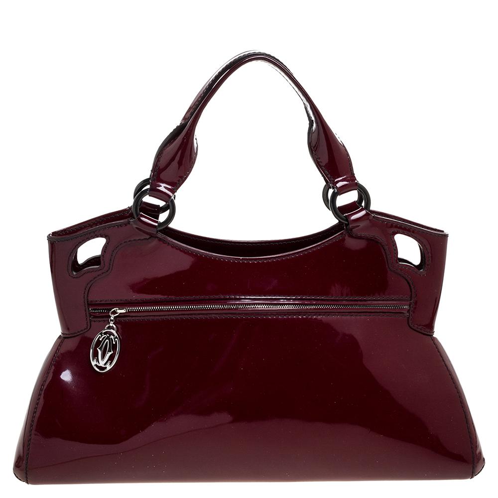 This Cartier beauty arrives in a gorgeous shape and design. It has a patent leather body with the logo detailed on the exterior and is held by two handles. The zipper secures the fabric interior and overall, the bag looks ready to lift your elegant