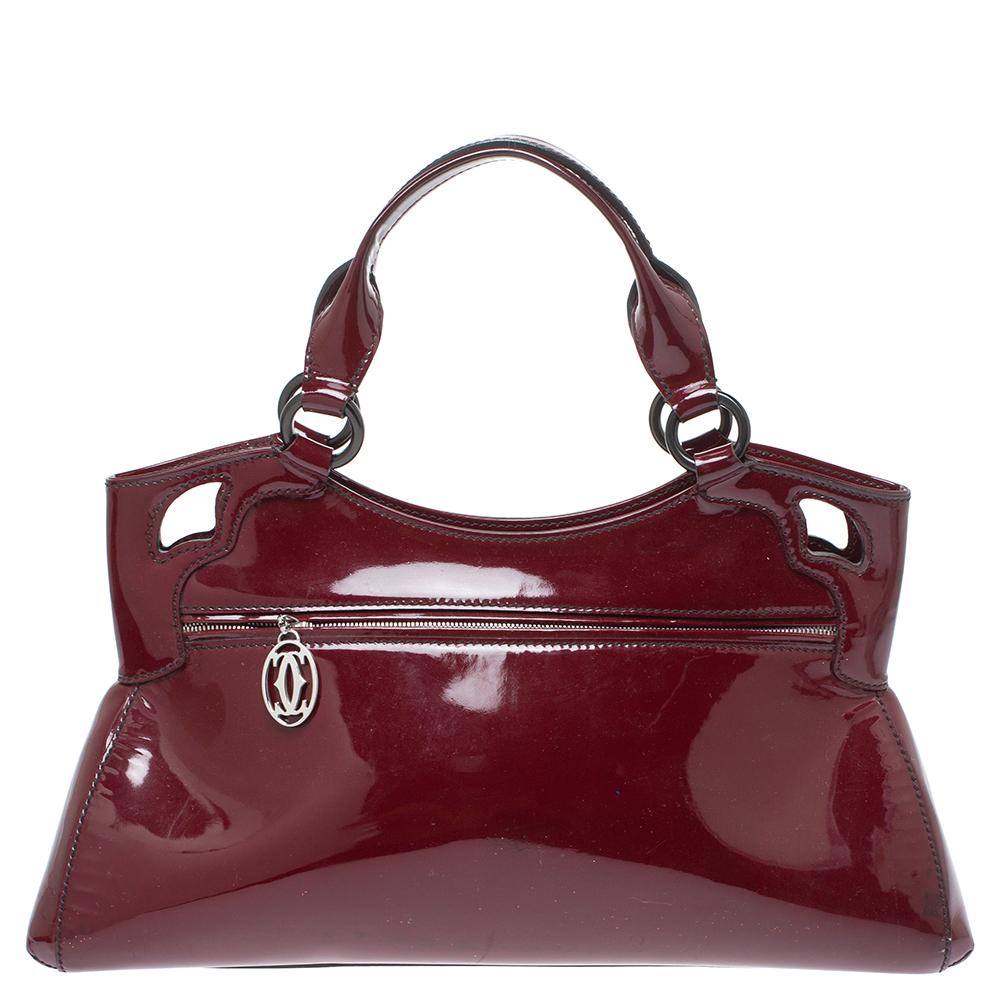 This Cartier beauty arrives in a gorgeous shape and design. It has a patent leather body with the logo detailed on the exterior and is held by two handles. The zipper secures the fabric interior and overall, the bag looks ready to lift your classic