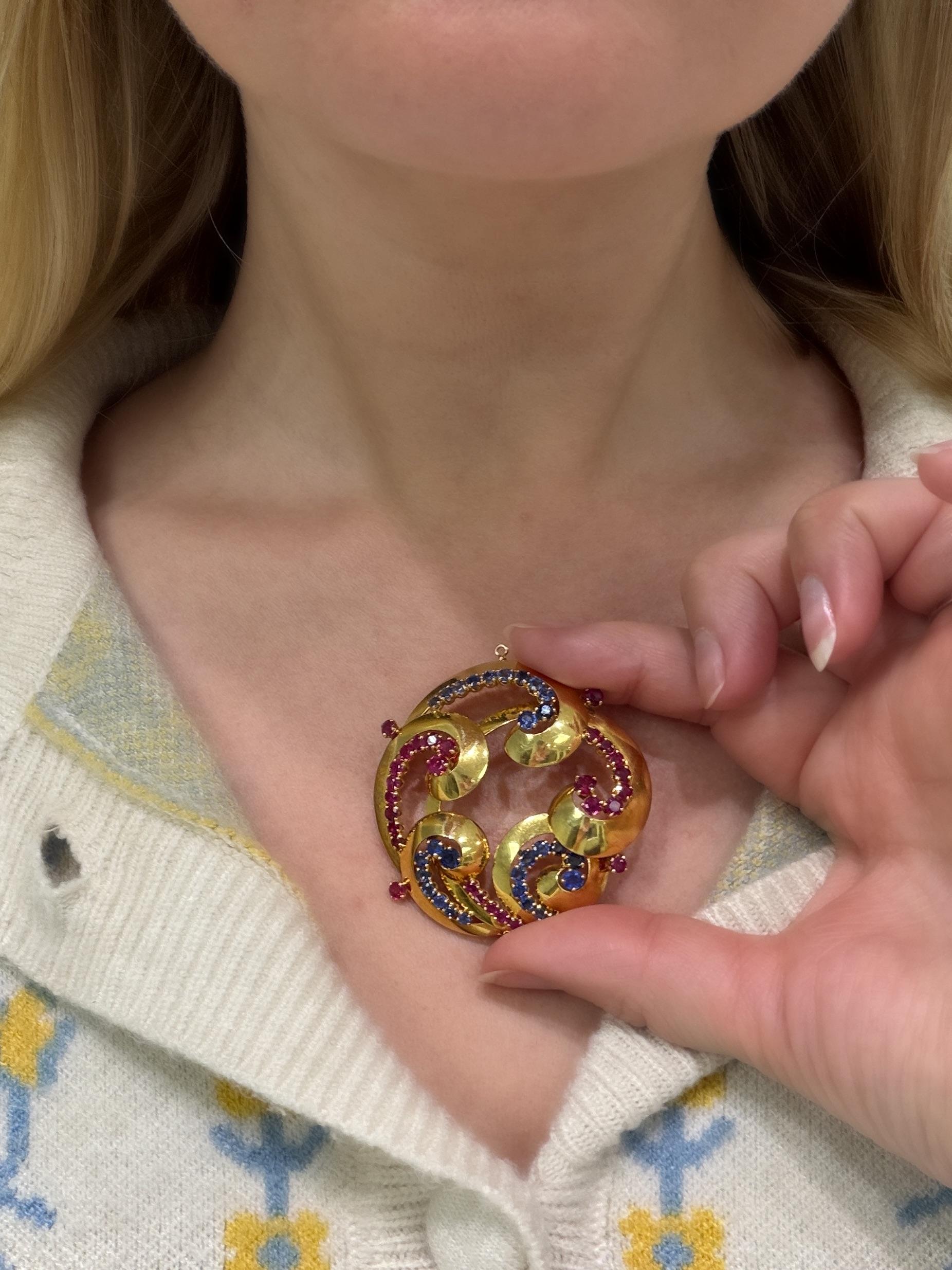 This unique retro Cartier pendant is in a billowing swirl design, very quintessential for the retro time period. Set with round mixed cut sparkling rubies and sapphires, they perfectly add a bit of color and interest to the piece. Mounted in 18