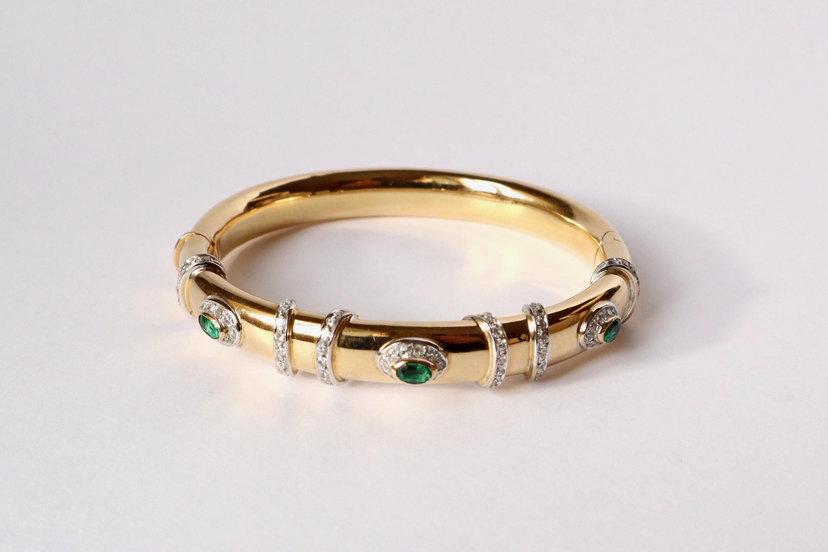 CARTIER Articulated rigid Cartier bracelet, opening in 18K yellow gold and white gold, 3 emeralds and diamonds. 
Bangle bracelet in 18 kt yellow gold decorated with three emeralds set with diamonds and separated by white gold rings set with