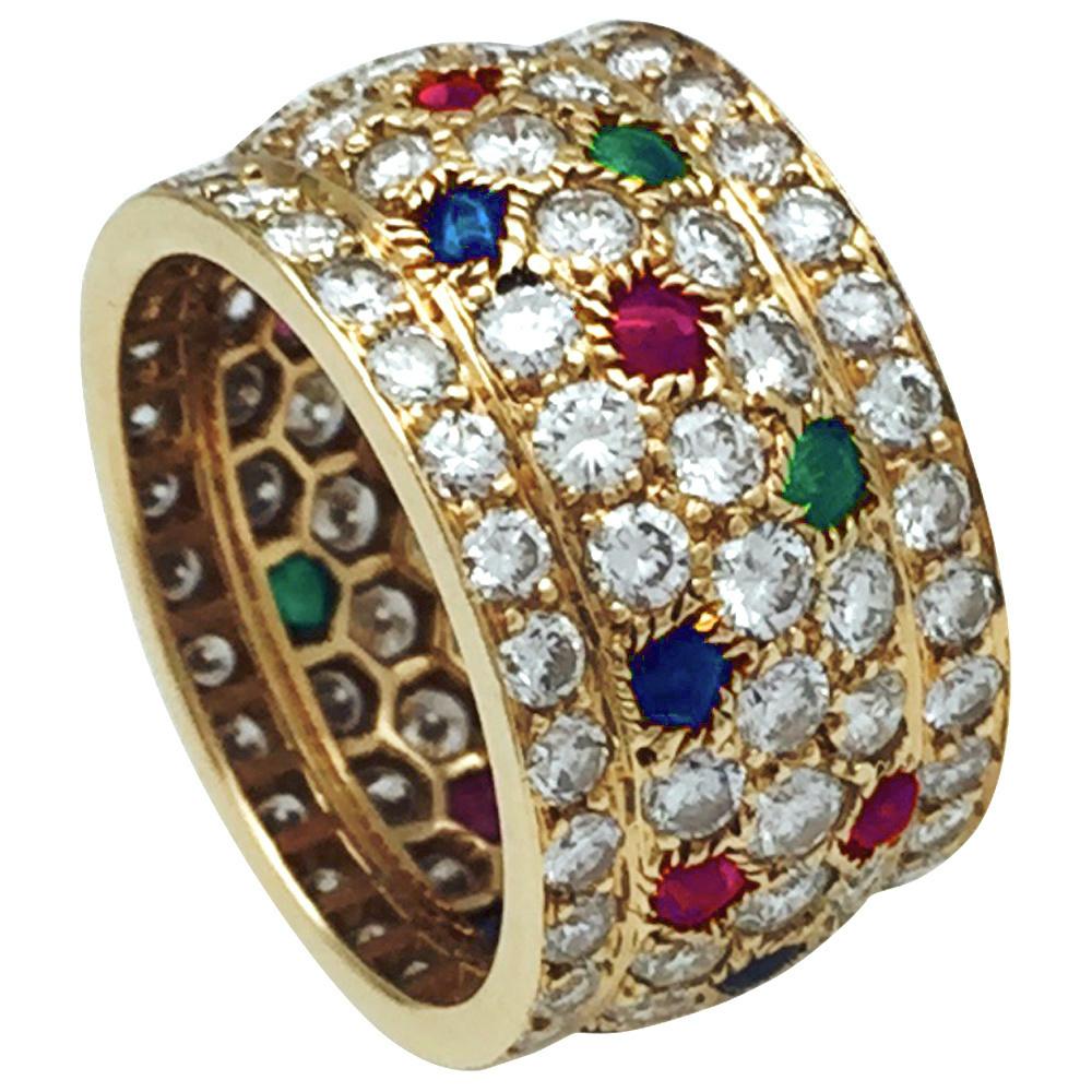 Yellow gold, 18Kt,  Cartier large ring, Nigeria collection, paved with brilliant cut diamonds and enhanced with cabochons emeralds, rubies and sapphires spots.
Total weight of diamonds : about 3.70 carats 
Width : 13 mm