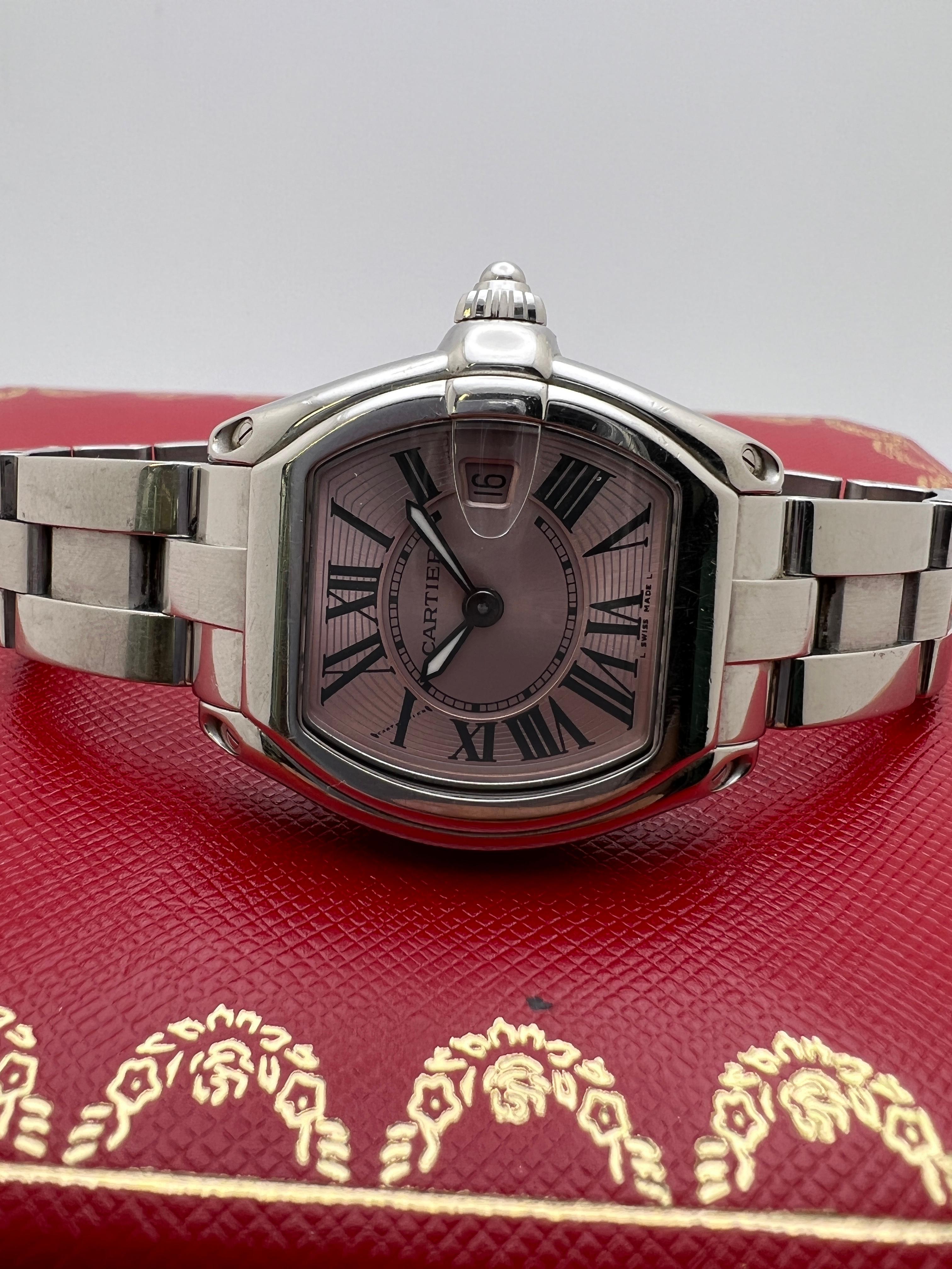 The Cartier Roadster W62017V3 is a distinctive and feminine take on one of Cartier’s most recognizable sport-luxury models. Crafted in polished stainless steel, the case features the signature tonneau shape with a magnified date bubble seamlessly