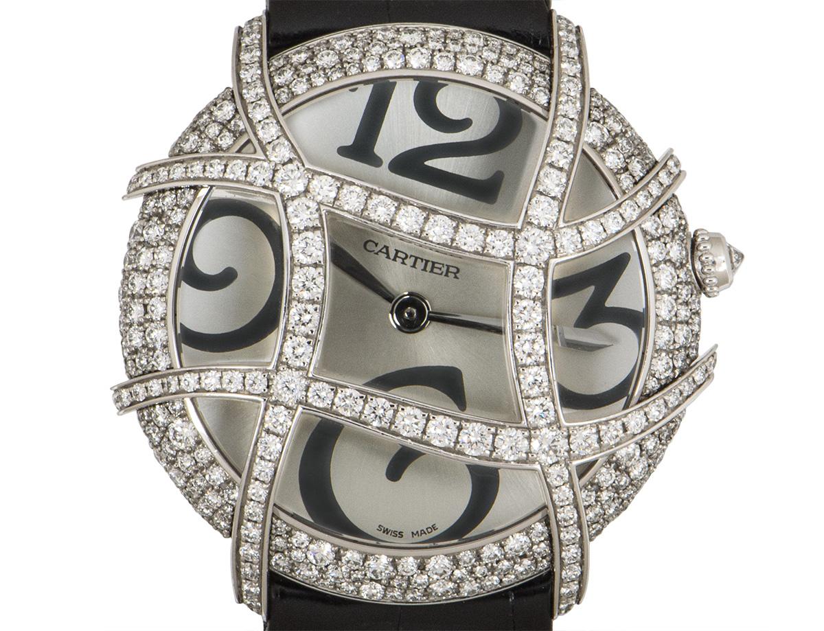 From Cartier, this 37 mm Ronde Folle Libre in white gold features a silver dial concealed by sapphire crystal. The dial is adorned with a curved white gold grid which is set with round brilliant cut diamonds, as is the bezel. A single round