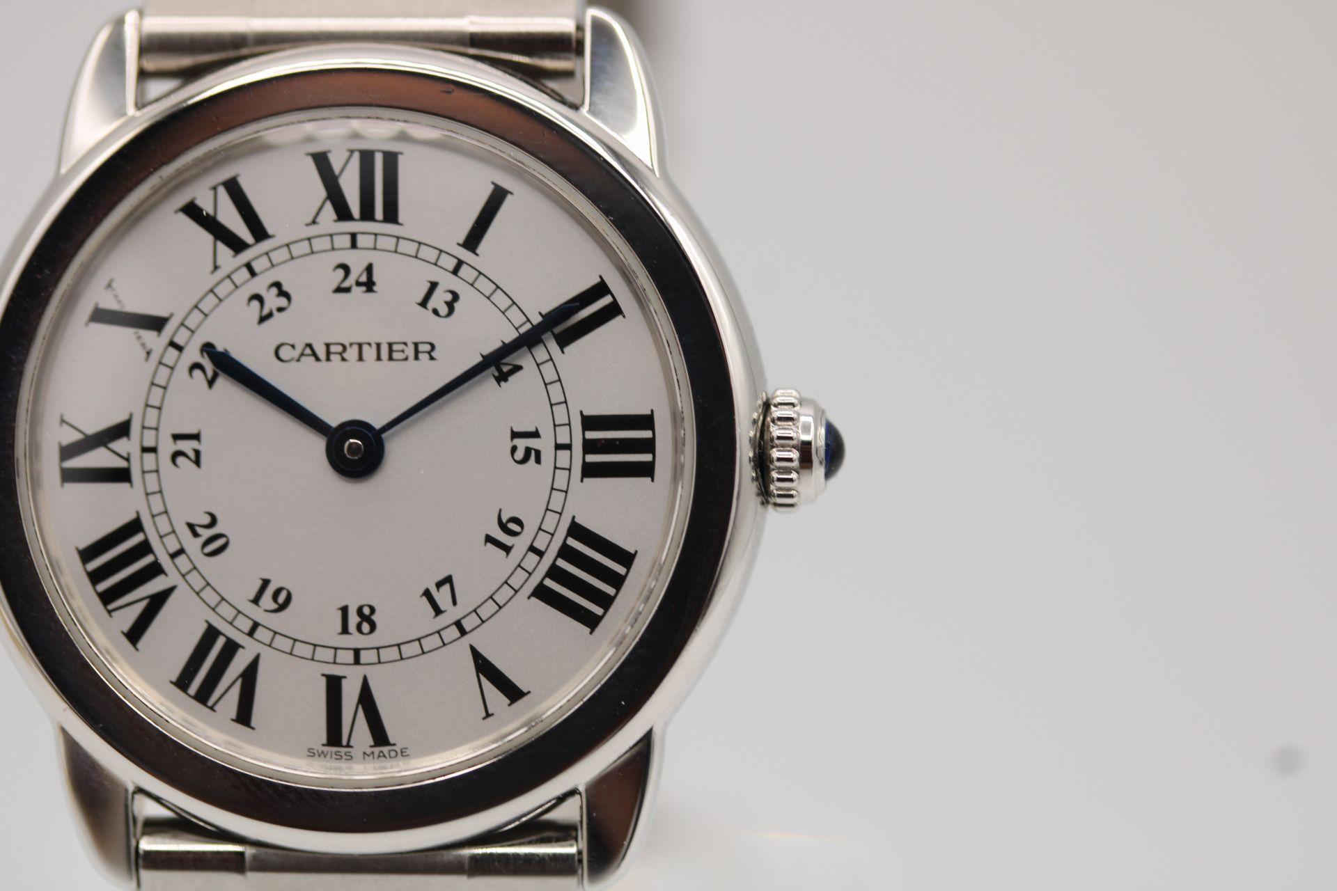 Classic Cartier with a twist, the Black Roman Numeral hour markers a signature of Cartier in a lesser case being a 29.5mm steel round case known as the 'Ronde Solo' one of the more modern designs to be released by Cartier. One of the most recent