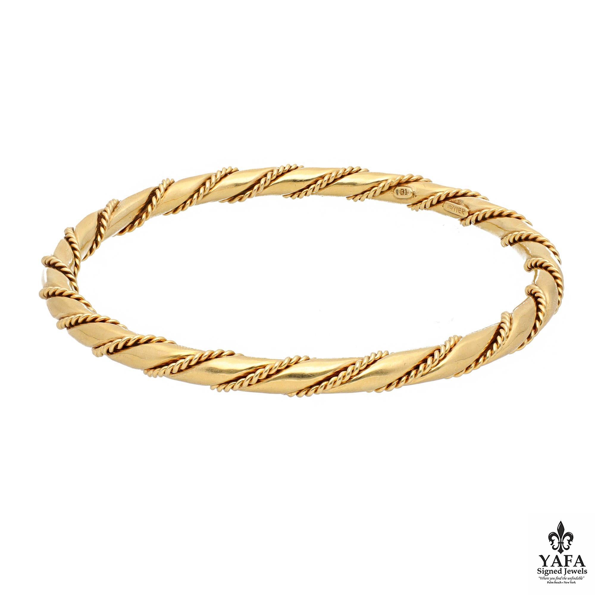 18K Yellow Gold Semi-Oval Twisted Bangle. The bangle consists of two twisted tubes: a thicker, smooth finish and a thinner, rope-style texture.

Circa - 1980
French Assay Marks
Signed - Cartier