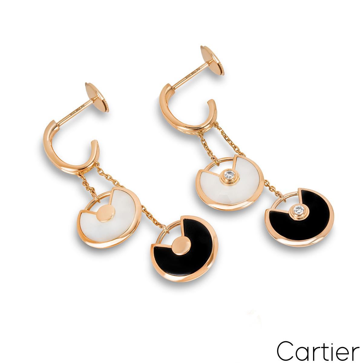 A charming pair of 18k rose gold onyx, mother of pearl and diamond earrings by Cartier from the Amulette de Cartier collection. The earrings comprise of two circular talismans suspended from a fine link chain at staggered lengths. The top talismans