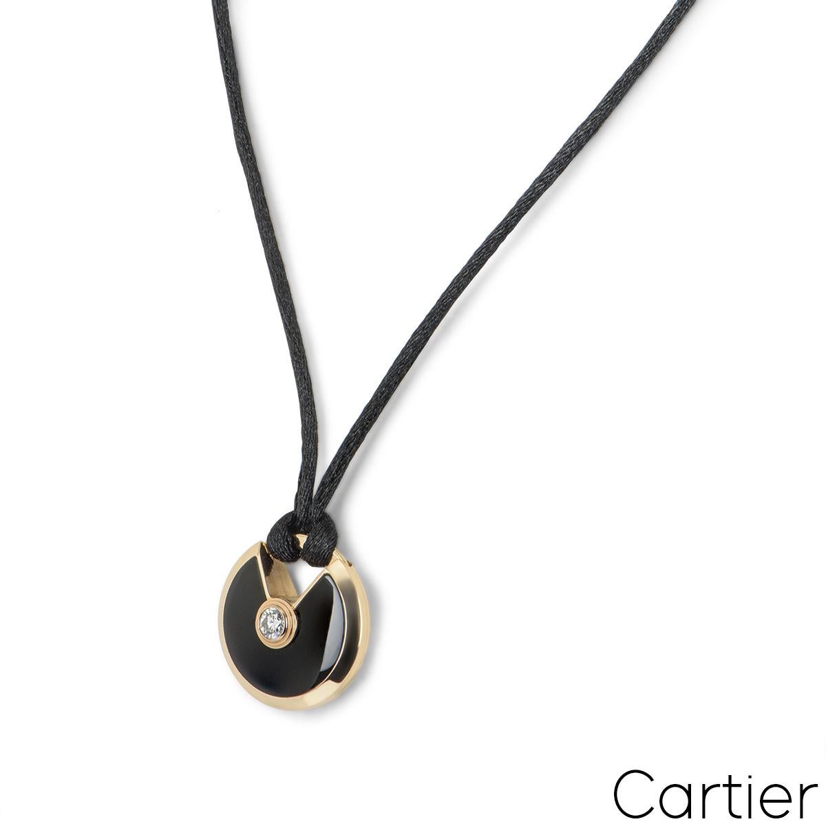 Pendentif Cartier en or rose 18 carats de la collection Amulette de Cartier. Le pendentif se compose d'un talisman circulaire, serti d'onyx et complété par un diamant rond de 0,09ct de taille brillant, en serti clos. Le talisman est suspendu à une