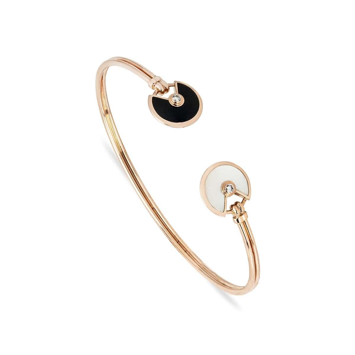 An 18k rose gold mother of pearl and onyx Amulette de Cartier bracelet by Cartier. The bracelet comprises of two iconic Amulette motifs, one featuring an onyx inlay and the other mother of pearl Both are set to the centre with a single round