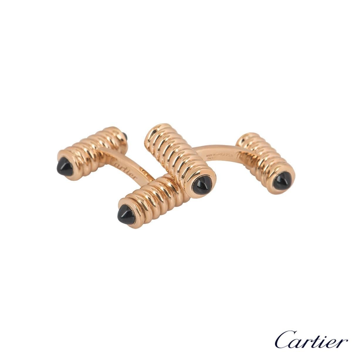 An alluring pair of 18k rose gold and onyx cufflinks by Cartier. The cufflinks feature two ribbed rose gold bars in different sizes with onyx beads on both ends. The cufflinks are encased together by a bar fitting with a length of 2.20cm, width of