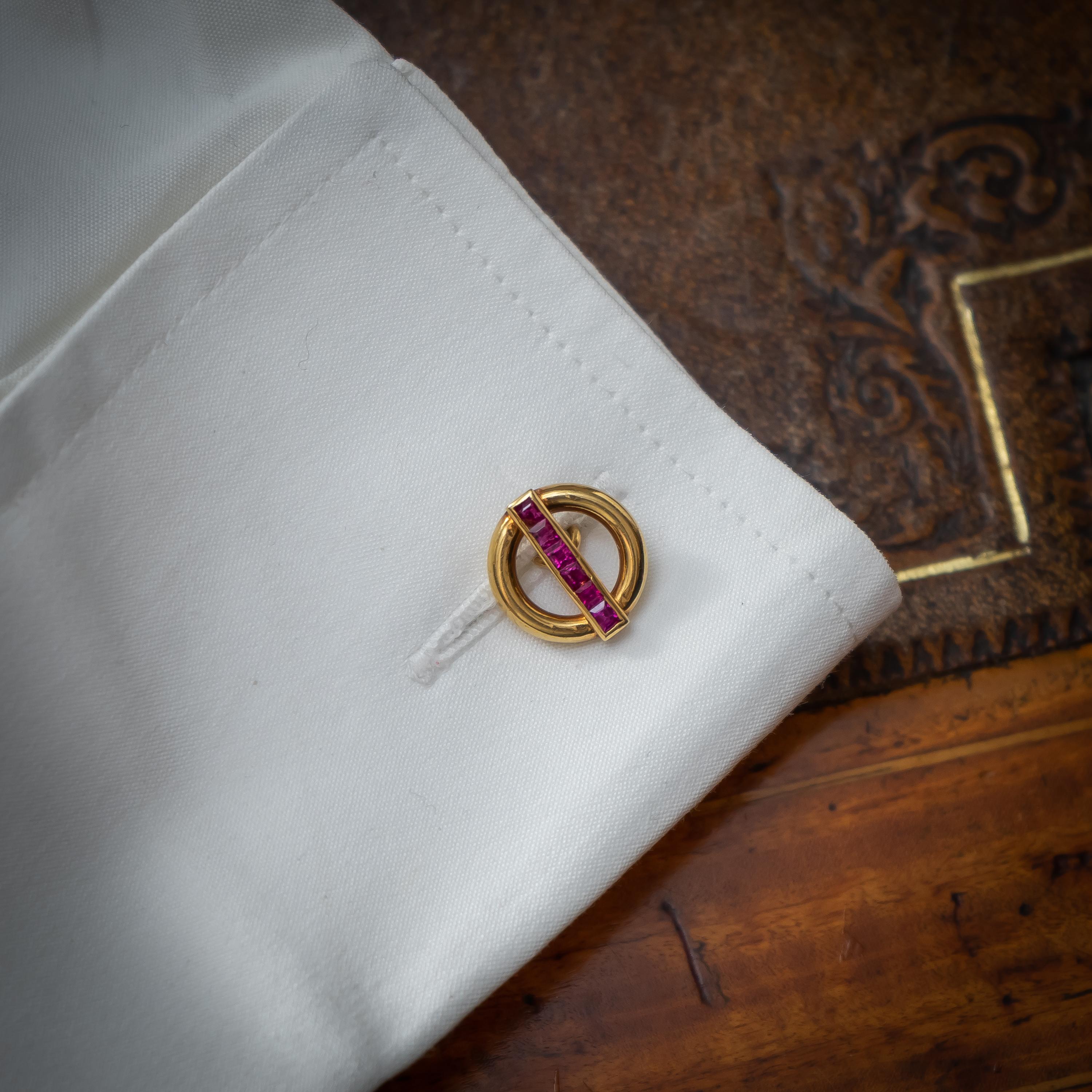 Ein Paar Vintage-Manschettenknöpfe von Cartier aus Gold und Rubin. Jedes der doppelten Glieder besteht aus einem offenen Kreis mit einer Reihe von quadratisch geschliffenen Rubinen, montiert in 18-karätigem Gold, signiert und nummeriert, um 1950.