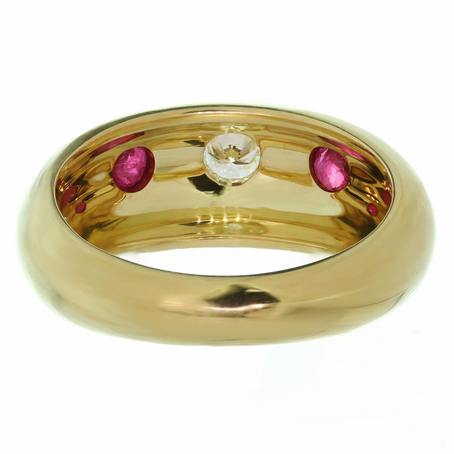 This chic Cartier Bombé band is crafted in 18k yellow gold and set an estimated 0.16 carat brilliant-cut round F-G VVS2-VS1 diamond and a pair of round rubies weighing an estimated 0.16 carats. The ring is signed Cartier and numbered. Made in France