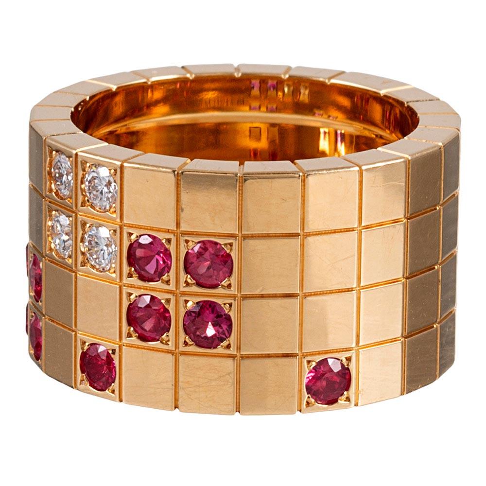 Offering a fun play on geometry, this wide 18 karat yellow gold band is decorated with a block pattern and asymmetrically decorated with 11 faceted round rubies and 4 brilliant white diamonds. The ring measures nearly 13mm wide and is signed
