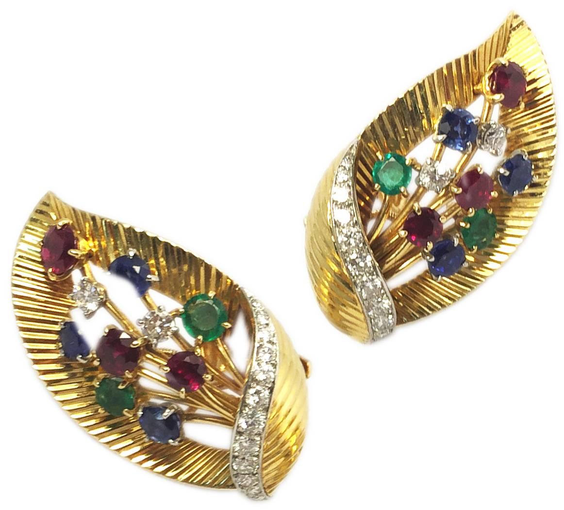 An exquisite pair of Cartier earclips in the shape of a leaf, embracing a floral bouquet of round cut rubies, sapphires, emeralds and diamonds. Made in 18kt yellow gold. Cartier Paris, circa 1950.