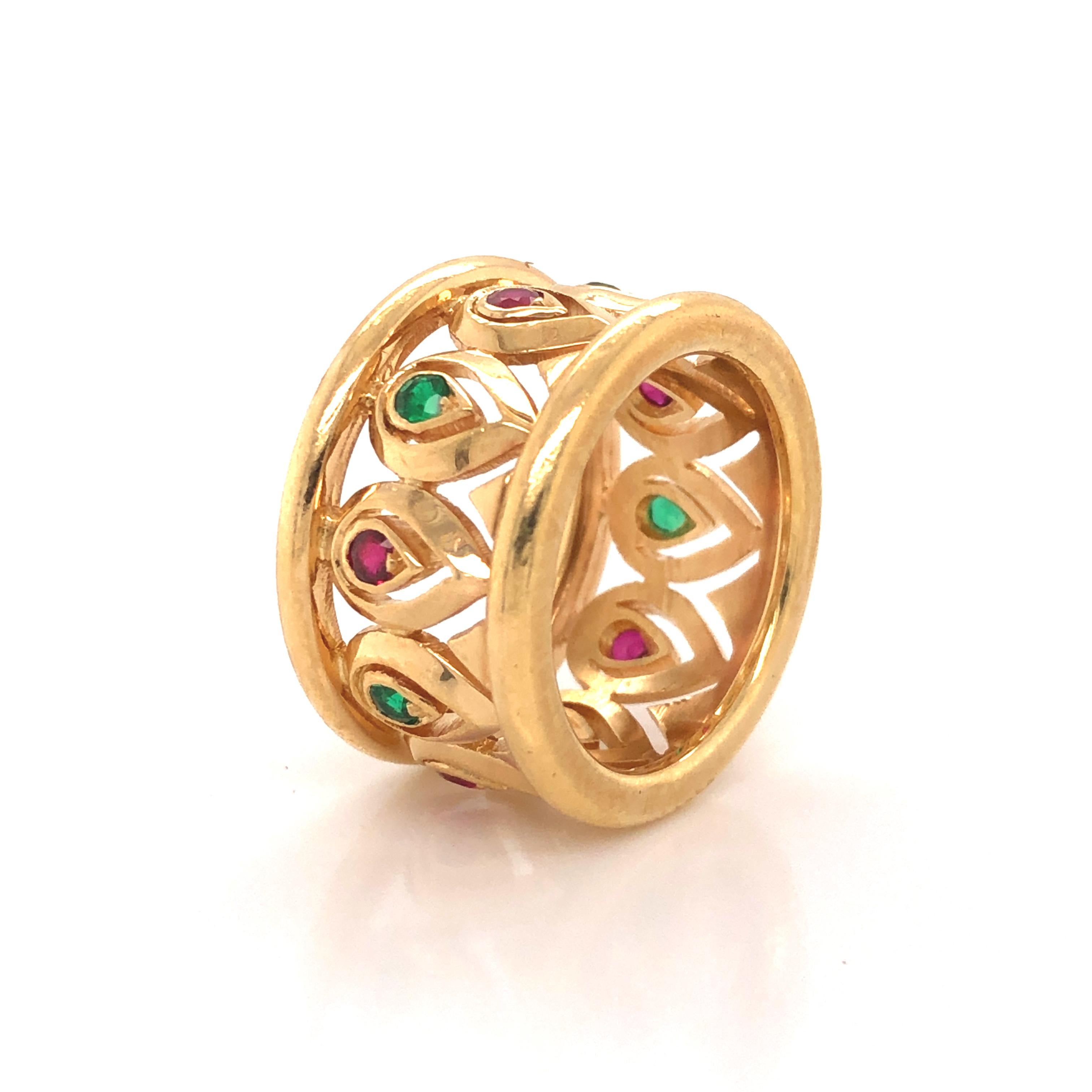 Beautiful wide band ring from Cartier. This elegant ring shows an amazing open work design crafted in 18k yellow gold. Set in a beautiful alternating pattern are natural ruby and emerald gemstones.  The workmanship on this ring is truly exceptional,