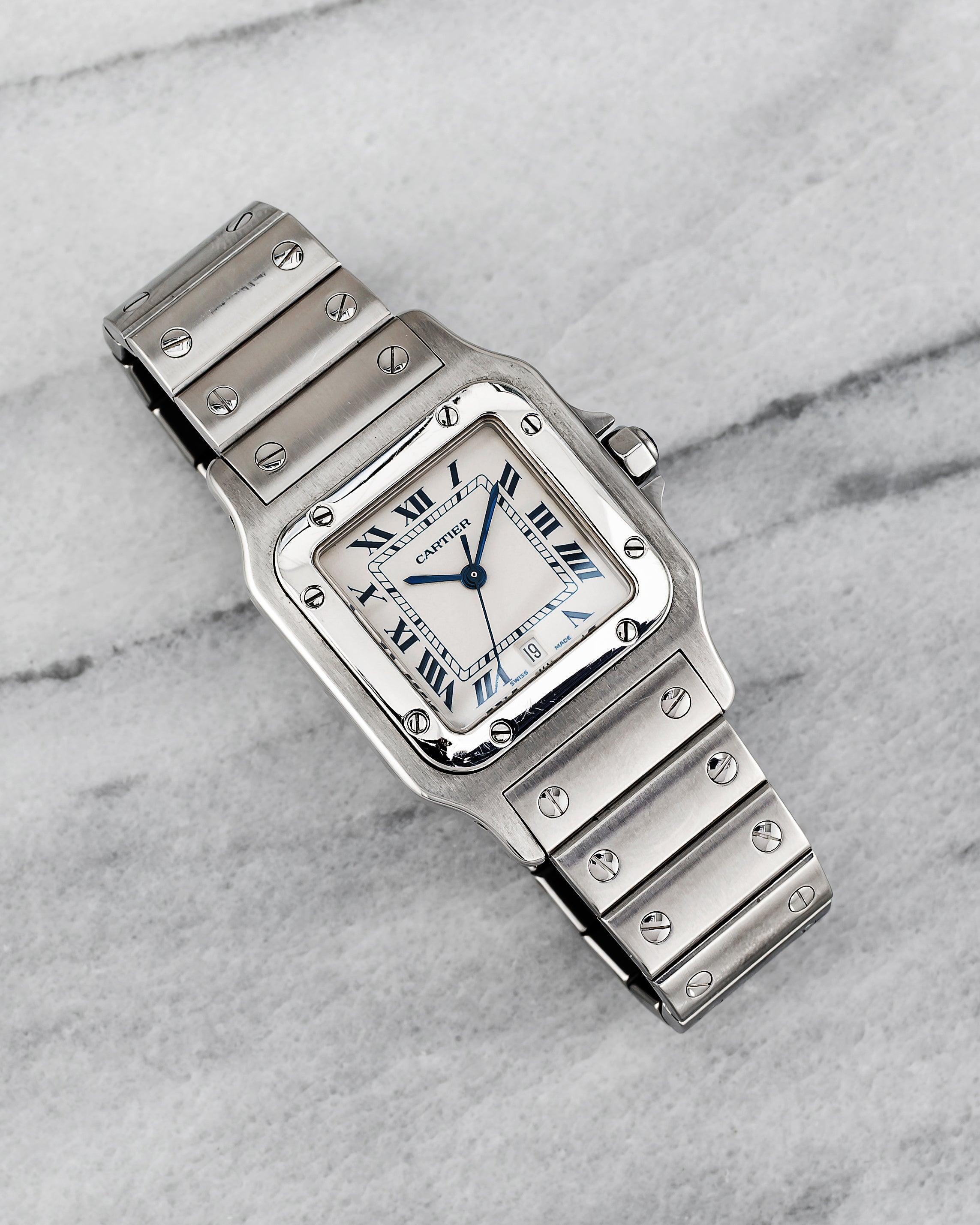 Voici une Cartier Santos référence 1564 vintage avec un cadran blanc en quartz des années 1980. Les dimensions comprennent un boîtier de 29 x 41 mm et un bracelet à fermoir papillon qui s'adapte à un poignet de 6,75 pouces maximum. Cadran bleu à