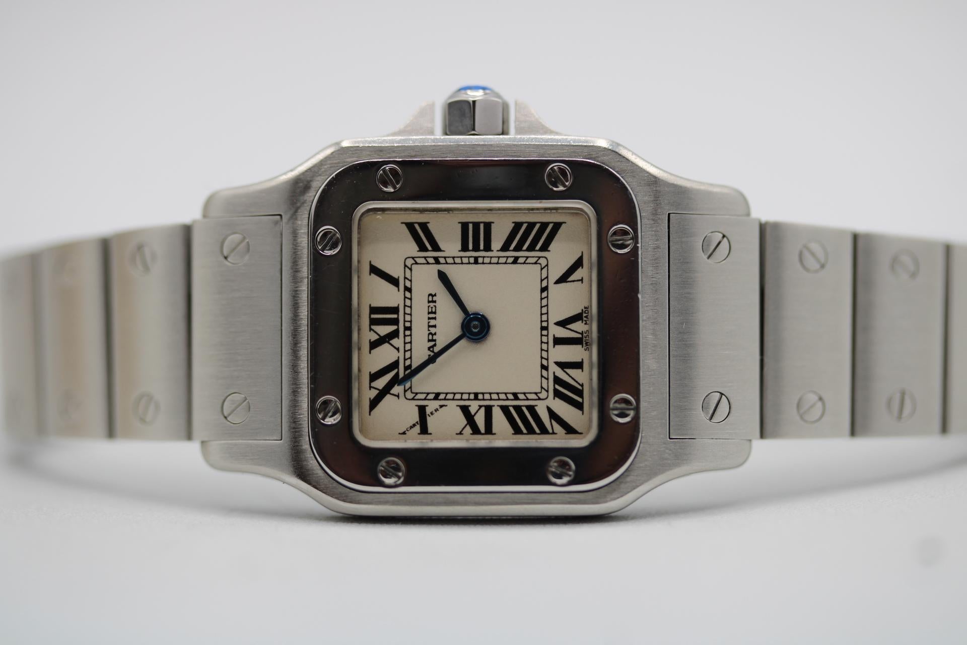 Il Cartier Santos 1565 rappresenta lo stile tipico di Cartier, elegante e di classe. Questo Santos è il modello da 24 mm, il più piccolo, e funziona a batteria al quarzo. Grazie alla recente lucidatura completa e al cambio della batteria, l'orologio
