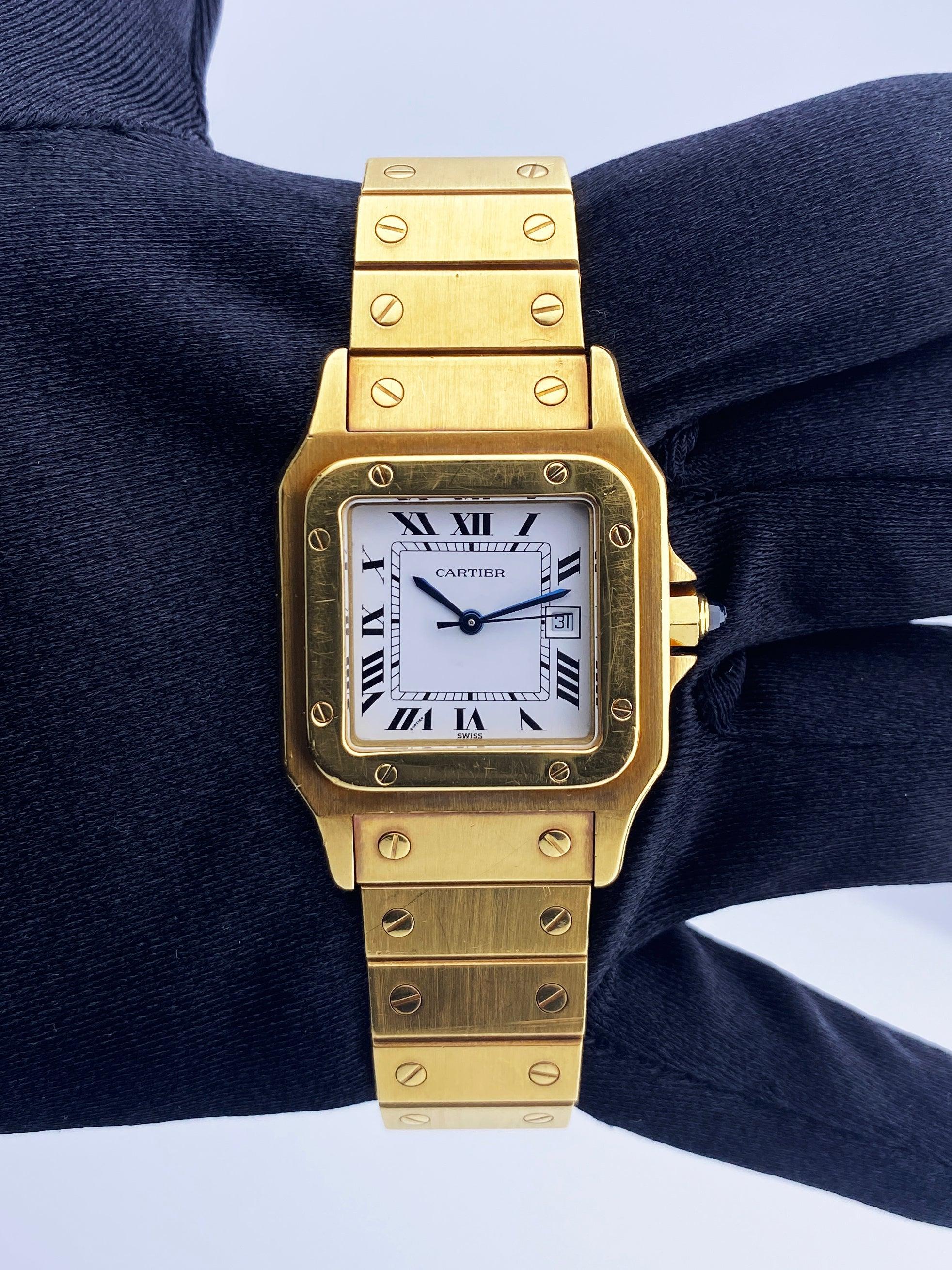 Cartier Santos Mens Watch. 29mm 18k yellow gold case. 18k yellow gold fixed bezel. White dial with blue hands and Roman numeral hour marker. Minute markers on the inner dial. Date display at the 3 o'clock position. 18k yellow gold bracelet with