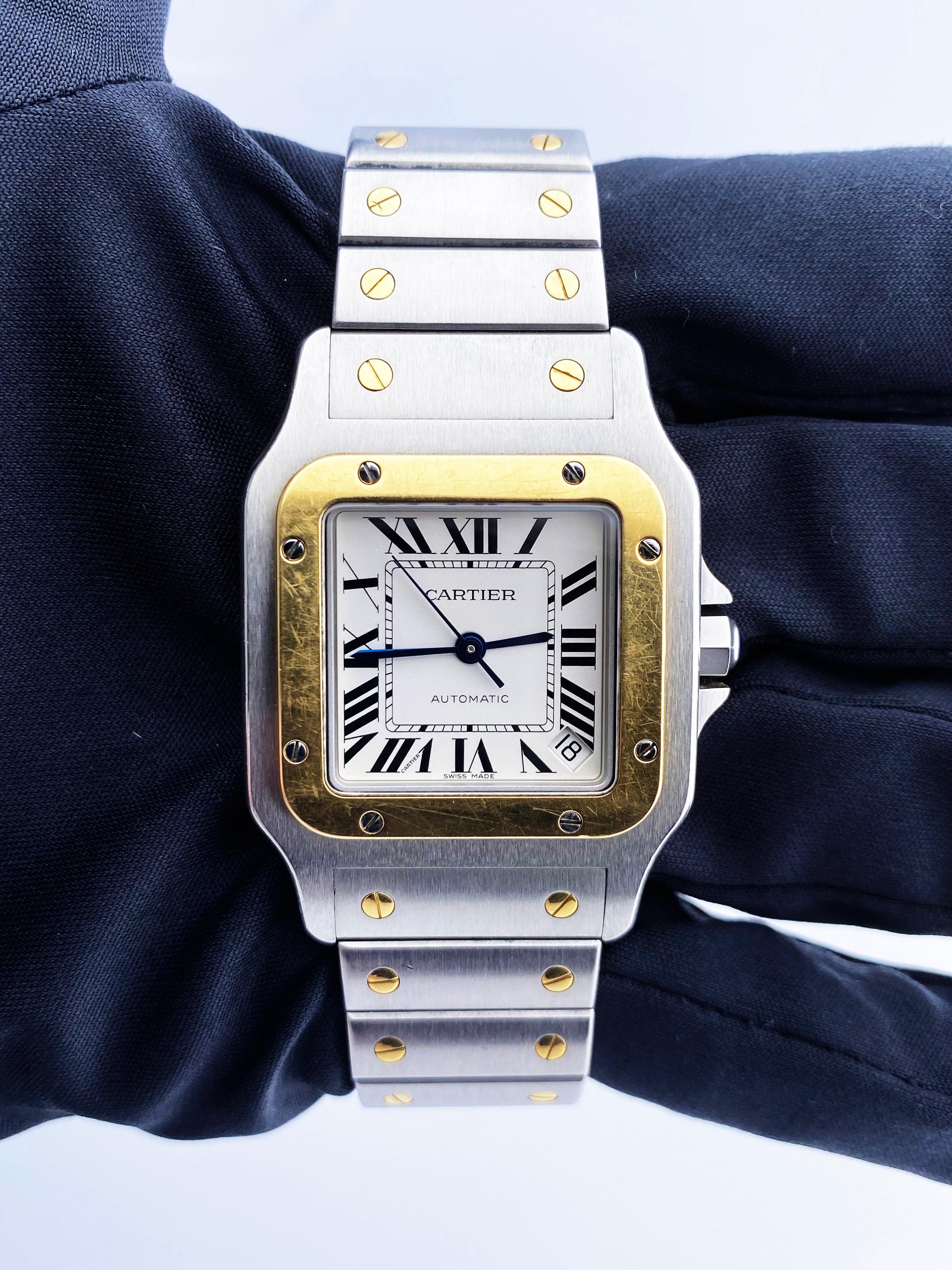 
Cartier Santos 2823 Mens Watch. 32mm stainless steel case. 18K yellow gold bezel. Off-white dial with blue steel hands Black Roman numeral hour markers. Minute markers around an inner dial. Date display between 4 and 5 o'clock position. 18K yellow