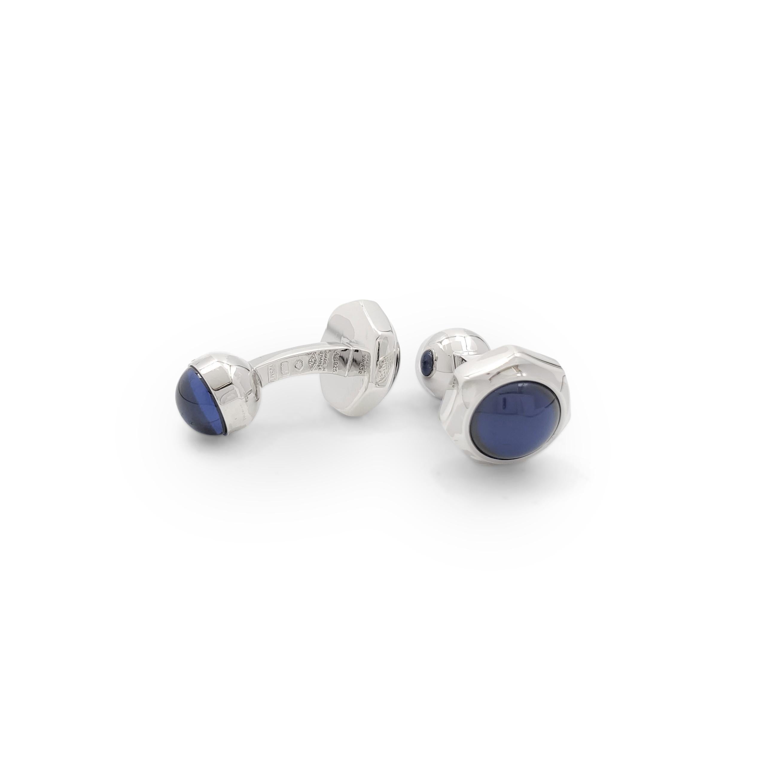 Authentic Cartier 'Santos de Cartier' cufflinks crafted in sterling silver. One end of the cufflink is a round high-polished silver half-sphere with a glowing, round cabochon synthetic spinel on top. This end has the Cartier signature. The other end