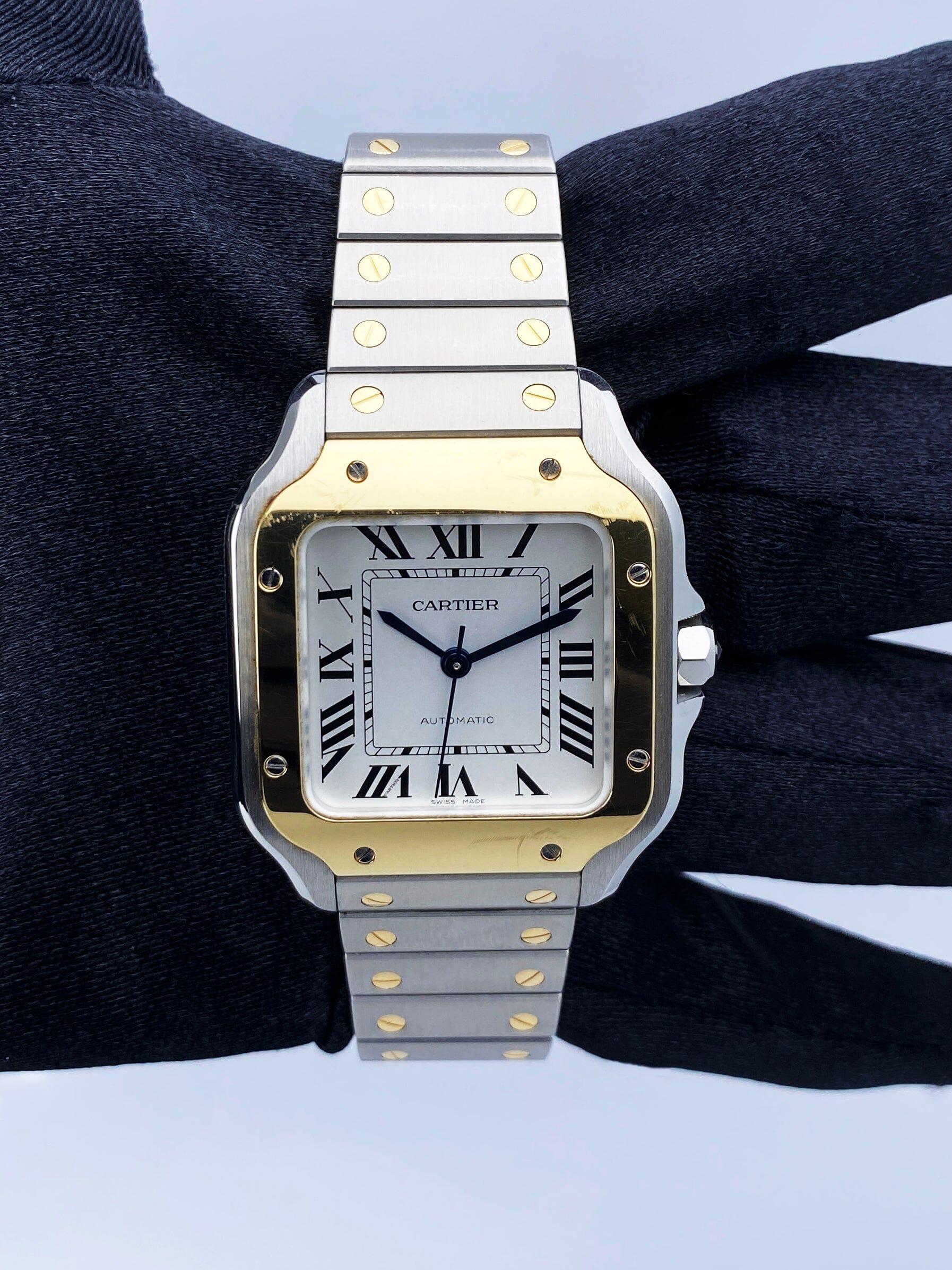 Cartier SantosDe Cartier W2SA0016 / 4075 Montre Femme. Boîtier en acier inoxydable de 35 mm avec lunette fixe en or jaune 18K. Cadran argenté avec aiguilles en acier bleu et index en chiffres romains noirs. Index des minutes sur le cadran intérieur.