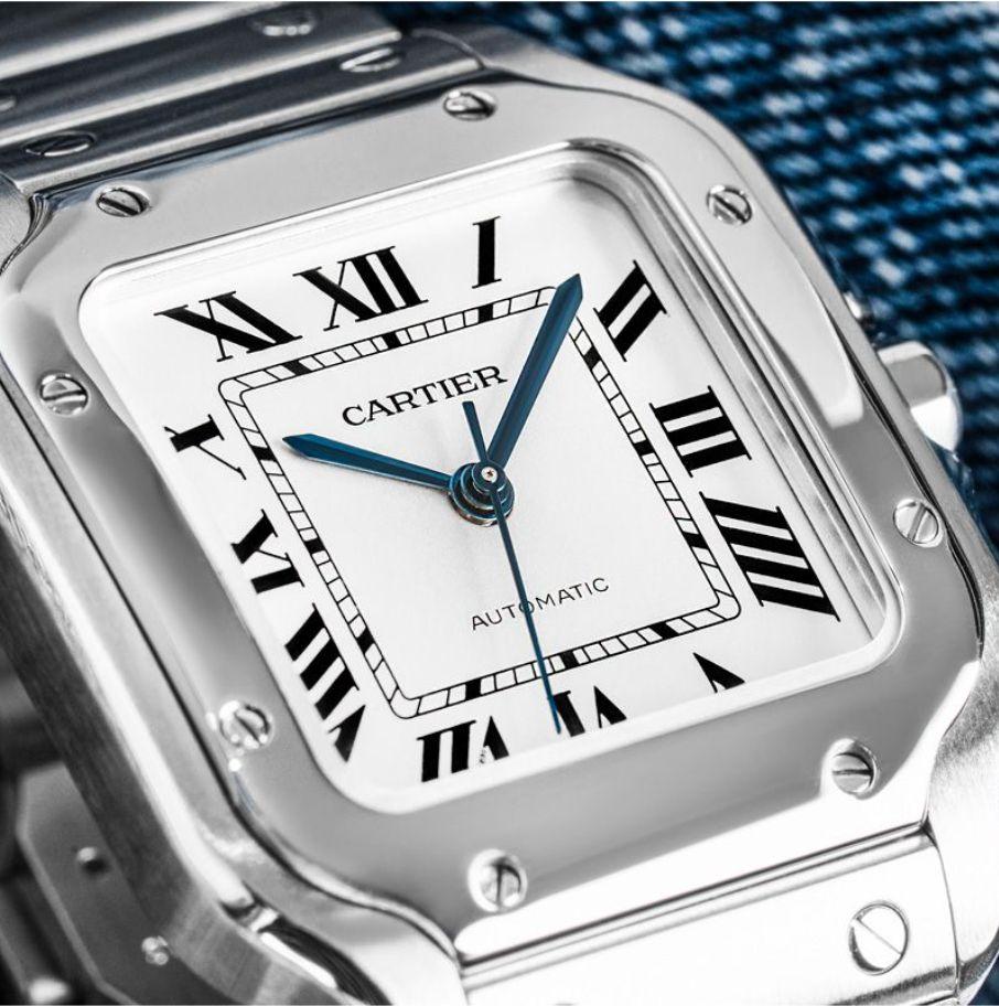 A medium Santos wristwatch by Cartier in stainless steel. Featuring a silver dial with roman numerals, a hidden Cartier signature at VII and steel sword-shaped hands. Complementing the dial is stainless steel bezel set with 8 screws and a crown set