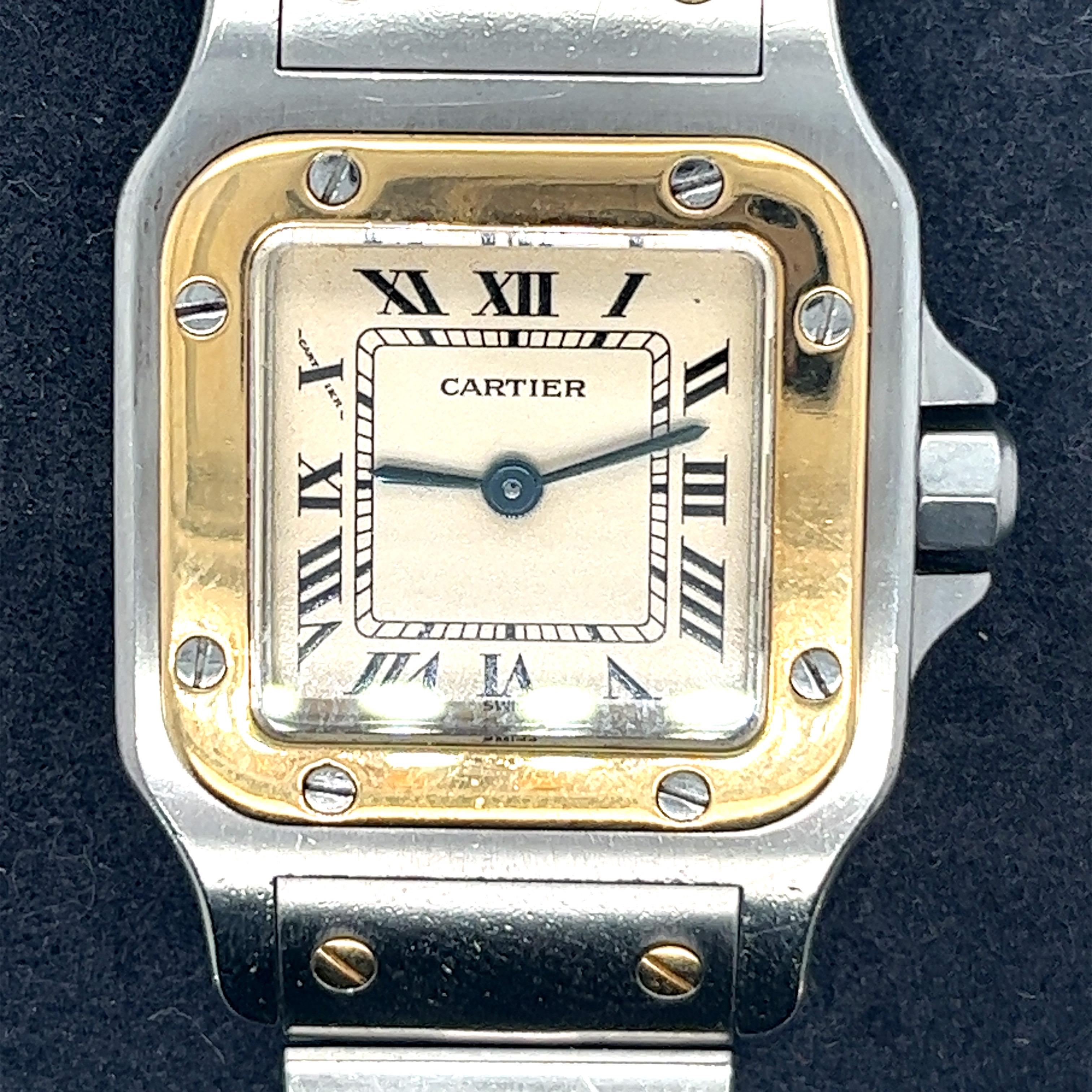 This is a stunning pre-owned Cartier  De Santos Watch Ref 1057930.  Crafted in stainless steel with an  18K yellow gold bezel. It has a silver dial with steel hands and  black roman numeral hour markers.  It has minute markers around an inner dial