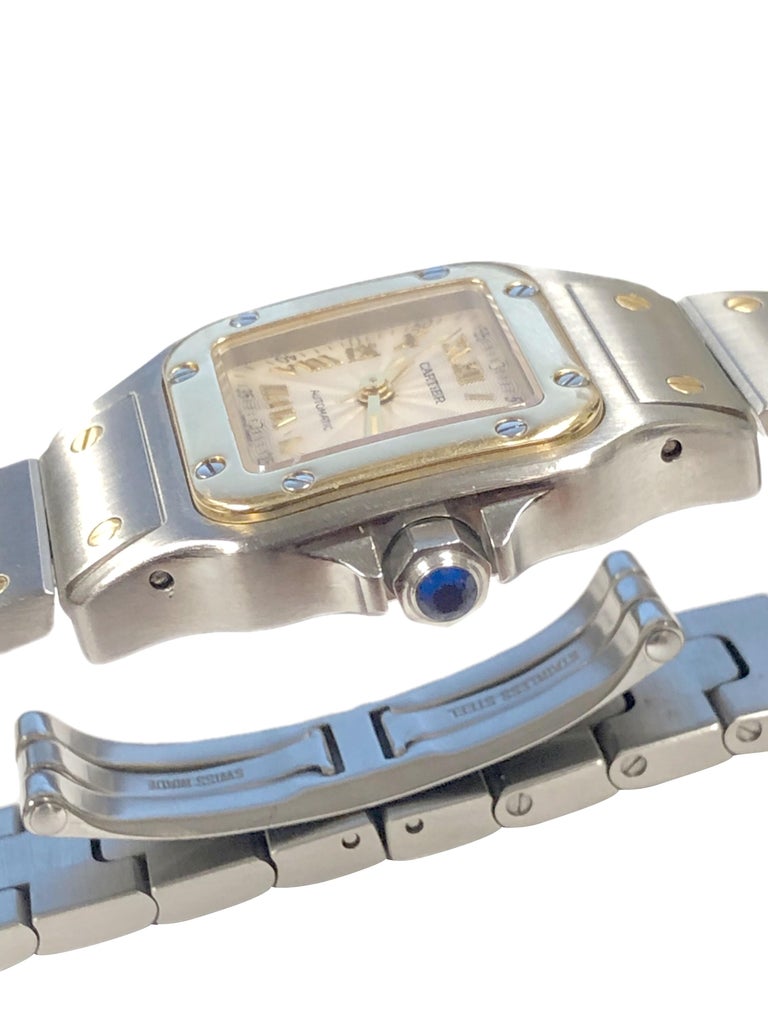 Circa 2005 Cartier Santos Ladies Wrist Watch, 34 X 24 MM Stainless Steel case with 18K yellow Gold Bezel. Automatic, Self Winding Movement, Silver Engine Turned Dial with raised Gold markers, Calendar window at the 5 position and a sapphire crown.