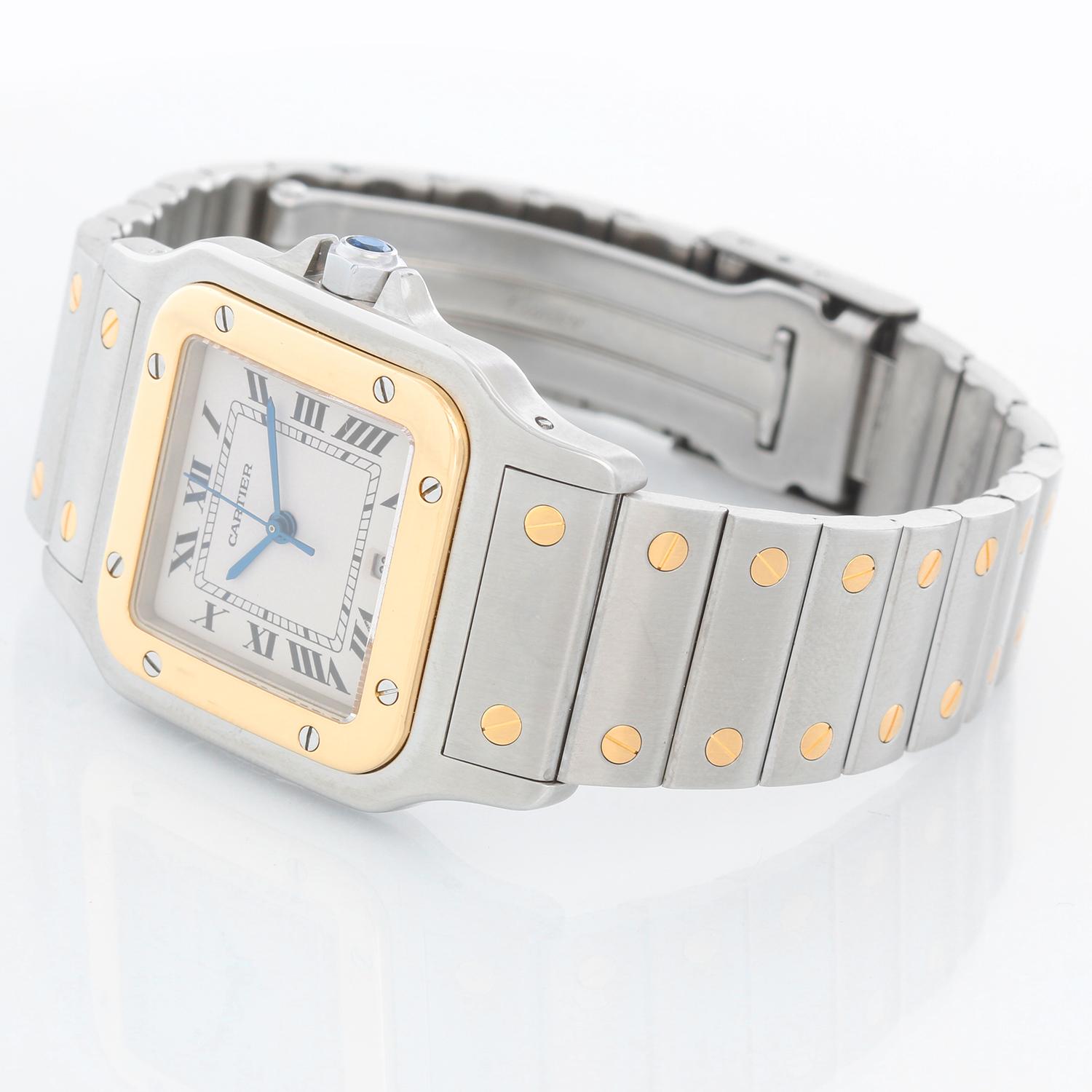 Cartier Santos Galbee Steel & Gold Men's Quartz Watch  - Quartz. Stainless steel case with 18k gold bezel  (28mm x 40mm). Ivory colored dial with black Roman numerals; date at 6 o'clock. Stainless steel and 18k gold Santos bracelet. Pre-owned with