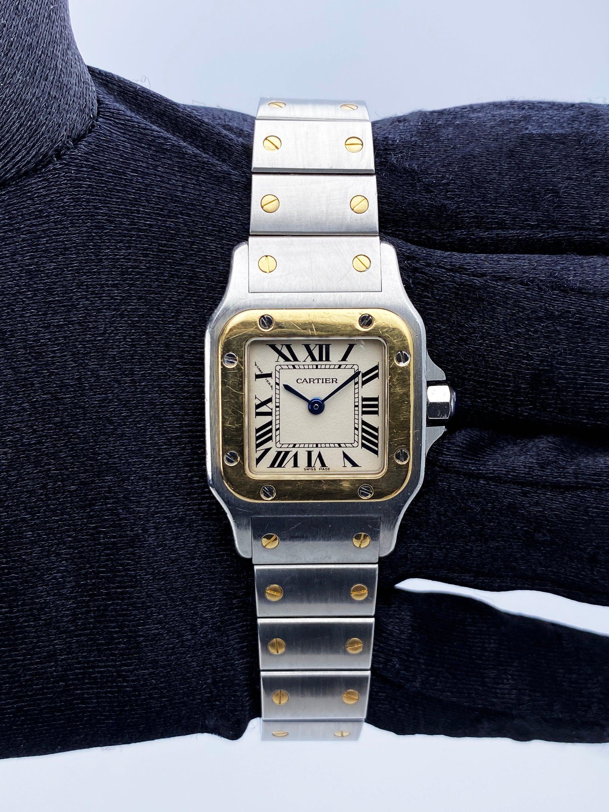 Cartier Santos Galbee W20012C4 Ladies Watch. 24mm stainless steel case. 18K yellow gold fixed bezel. Off-White dial with blue hands and Roman numeral hour marker. 18K yellow gold & stainless steel bracelet with hidden butterfly clasp. Will fit up to