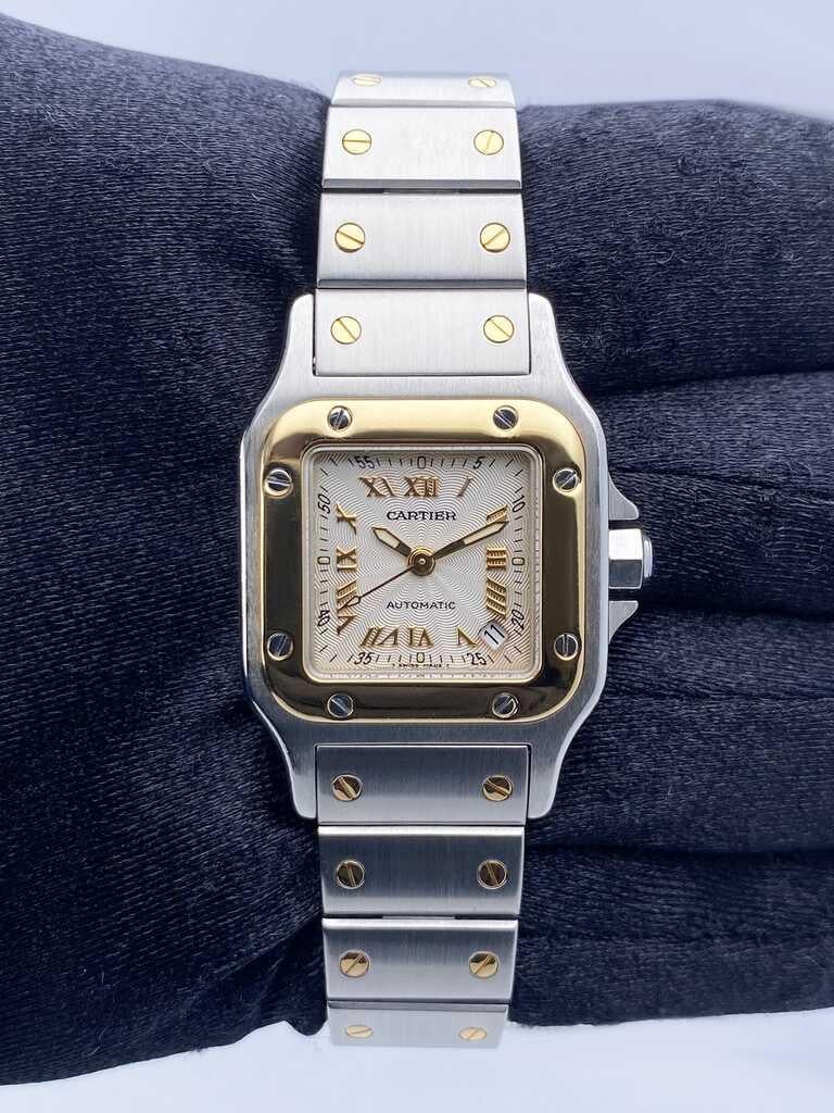 Cartier Santos Galbee W20045C4 / 2423 Ladies Watch. 24mm stainless steel case. 18K yellow gold bezel. Textured Silver dial with¬†gold luminous hands and Roman numeral hour marker. Minute marker on the outer dial. Date display between 4 & 5 o'clock
