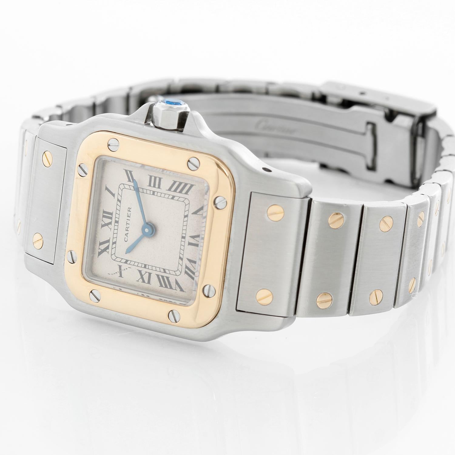 Cartier Santos Ladies 24mm Steel & Gold 2-Tone Quartz Watch - Quartz. Stainless steel case with 18k yellow gold bezel (24mm x 34mm ). Ivory dial with black roman numerals. Stainless steel bracelet with gold accents (will fit apx. 6-1/4-in. wrist).