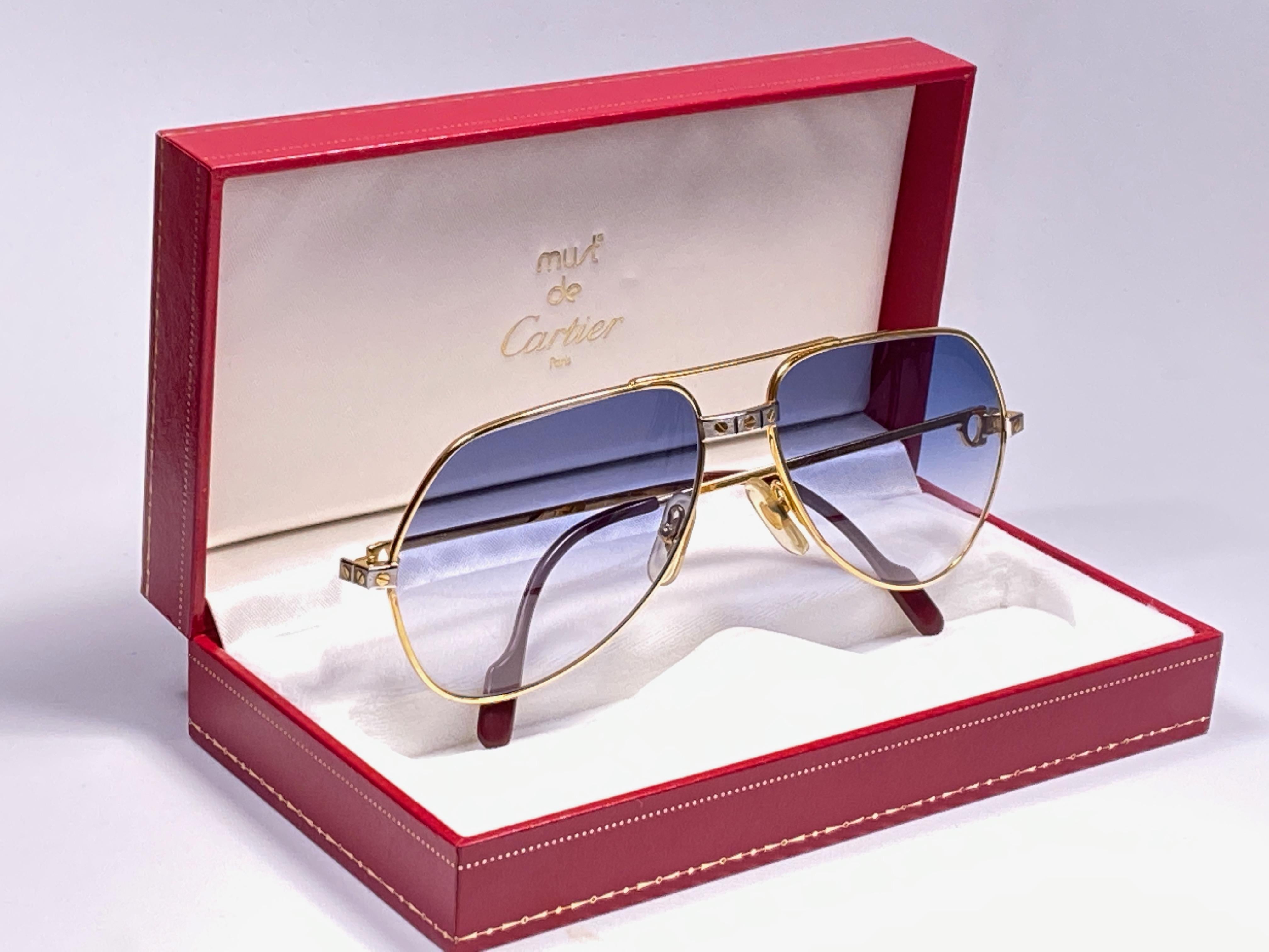 Von 1983!!! Cartier Aviator Santos Sonnenbrille mit individuell gestalteten blauen Verlaufsgläsern (UV-Schutz). 
Der Rahmen ist mit den berühmten Schrauben auf der Vorderseite und an den Seiten in Gelb- und Weißgold. Alle Markenzeichen. Rote Emaille