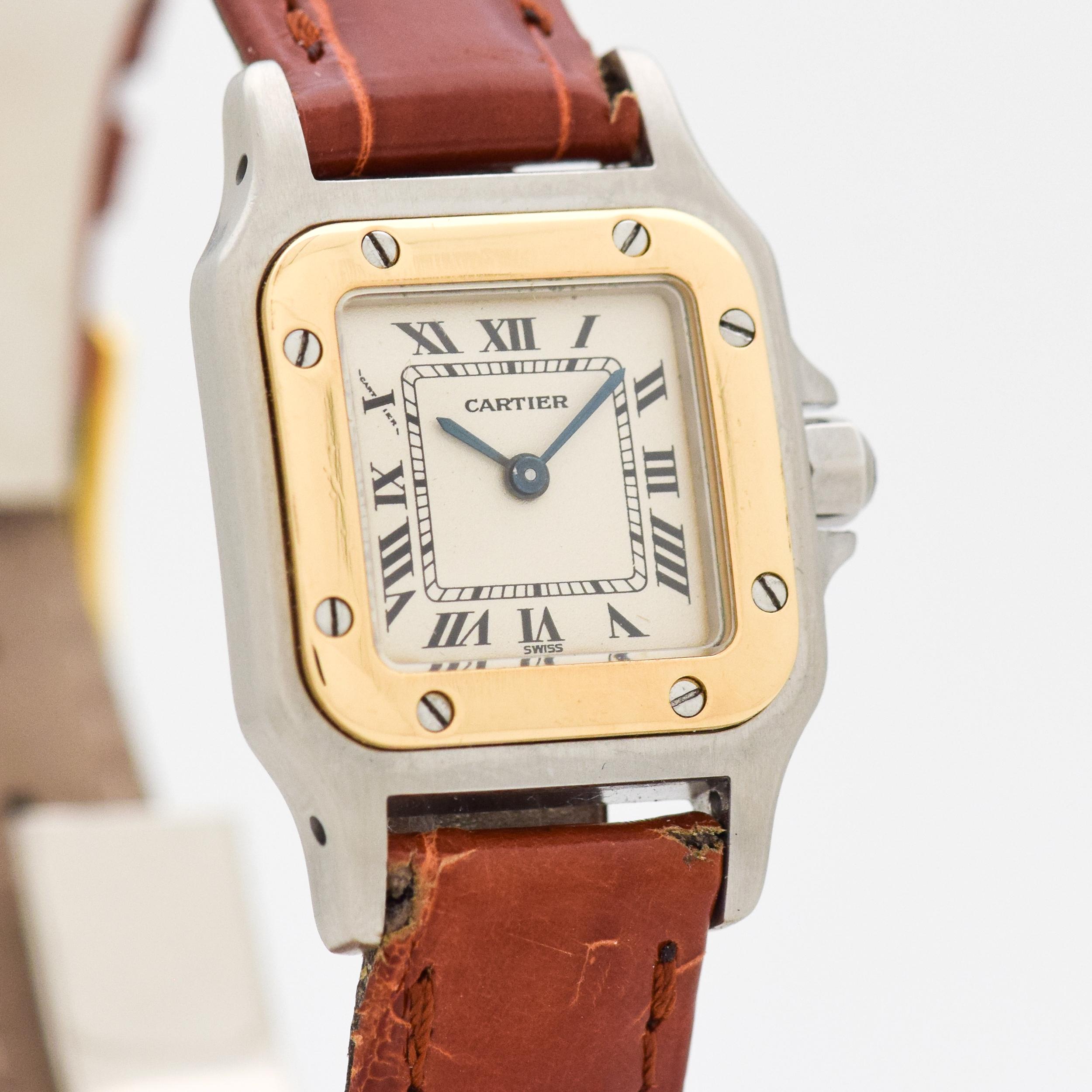 1990's Cartier Ladies Size Santos Two Tine 18k Yellow Gold and Stainless Steel watch with Original Silver Dial with Black Roman Numerals. 25mm x 34mm lug to lug (0.98 in. x 1.34 in.) - Quartz Movement. Equipped with a 100% Genuine Alligator Glossy
