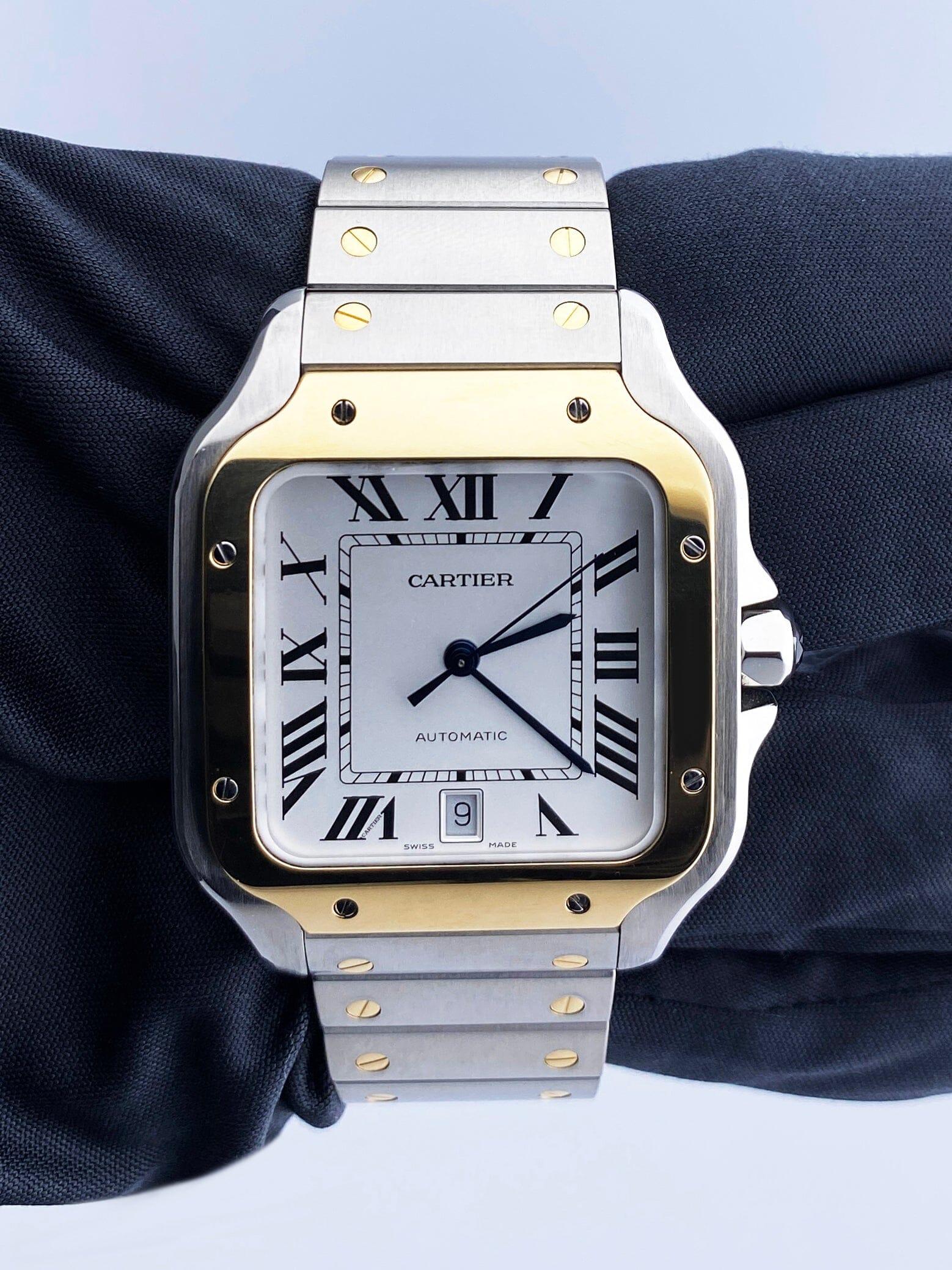 Cartier Santos W2SA0006 / 4072 Mens Watch. 40mm stainless steel case. 18K yellow gold bezel. Sliver dial with blue steel hands Black Roman numeral hour markers. Minute markers around an inner dial. Date display at 6 o'clock position. 18K yellow gold
