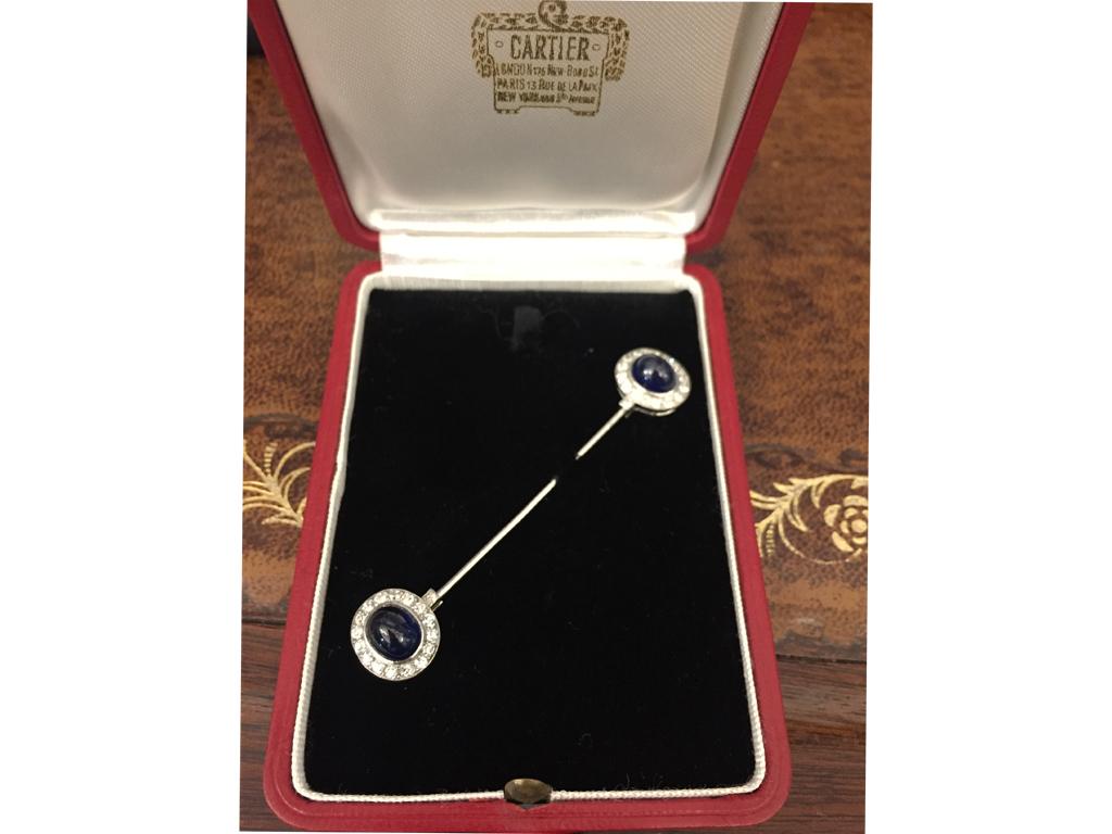 Cartier sapphire and diamond jabot pin. Set with two oval cabochon natural unenhanced sapphires in open back rubover settings with a combined approximate weight of 5.00 carats, surrounded by thirty six round eight cut diamonds in open back grain