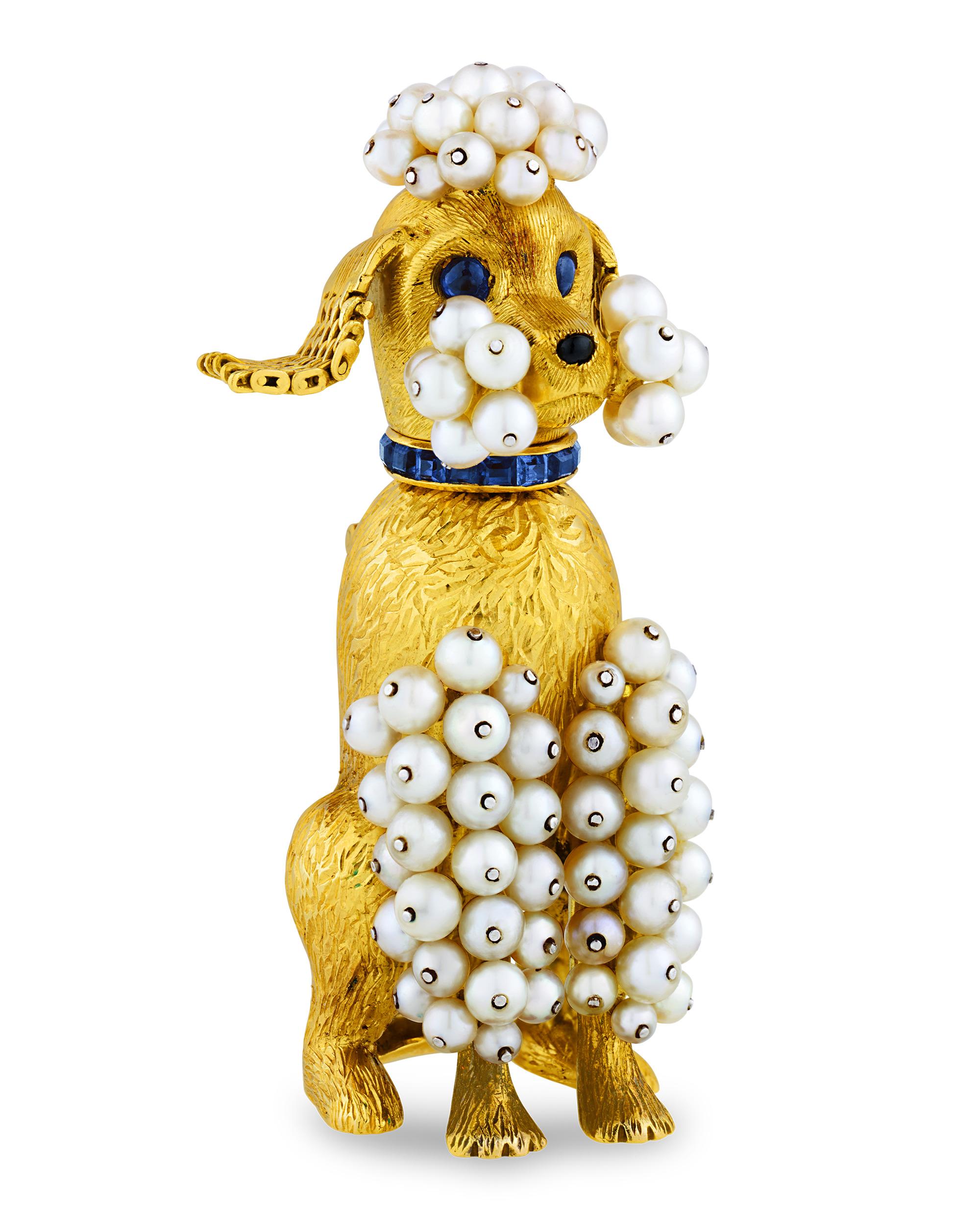 This delightful gold, sapphire and pearl poodle brooch showcases the more whimsical side of the legendary French jeweler Cartier. The playful yet elegant brooch features a poodle sitting at attention. The pooch is modeled from textured 18K gold and