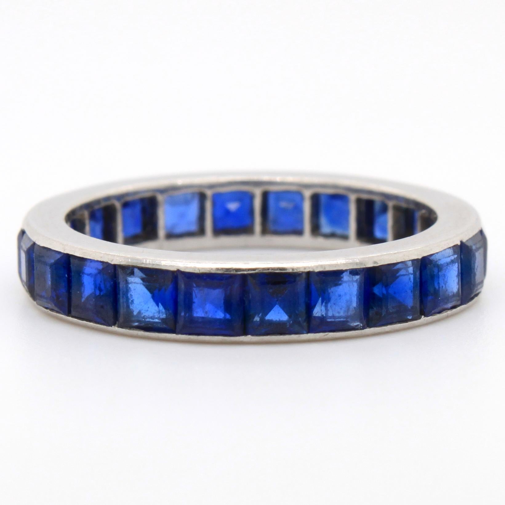 A eternity ring with square cut sapphires by Cartier. The sapphires have a beautiful blue colour and weigh approximately 2.5 carats. The ring has a rubbed but distinct Cartier signature. 

Ring size 53.