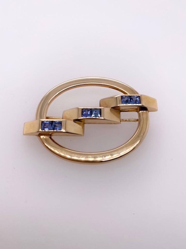 Very chic and elegant 14k gold  brooch, made and signed by Cartier.

Unusual oval configuration. Set with 6 French-cut sapphires which have a beautiful blue color. A perfect finishing touch.