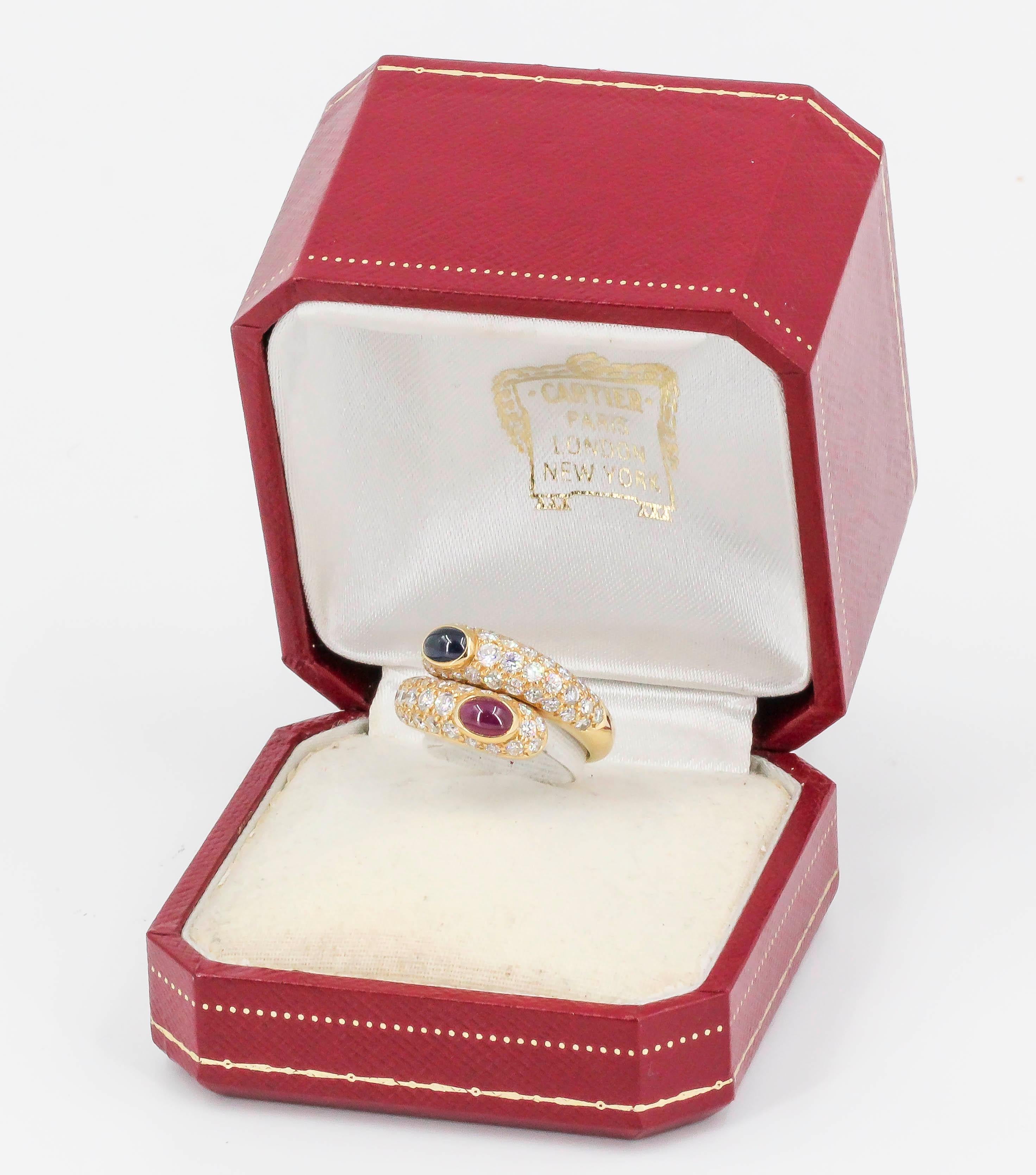 Stylish cabochon sapphire, cabochon ruby, diamond and 18K yellow gold ring by Cartier. It features high grade round brilliant cut diamonds with deep blue cabochon sapphire on one end and rich red cabochon ruby on the other. European size 53, approx.